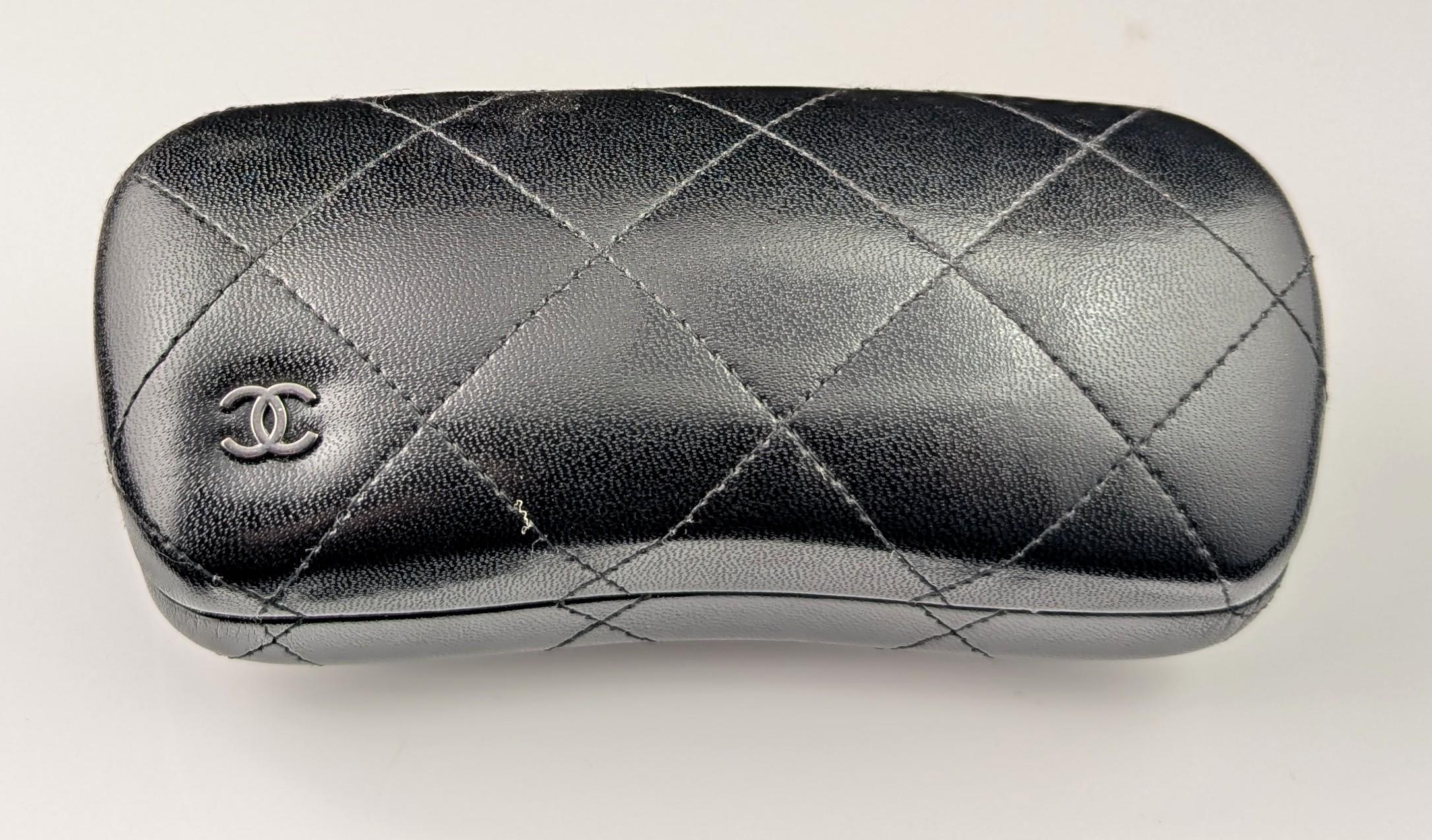 Eine wunderschöne Sonnenbrille von Chanel im Oversized-Stil.

Grau/blau getönte Gläser mit schwarzem und beigefarbenem Acetatrahmen mit Korbflechtmuster auf dem beigen und silberfarbenen CC-Logo an den Bügeln.

Seriennummer an den Innenbügeln und am