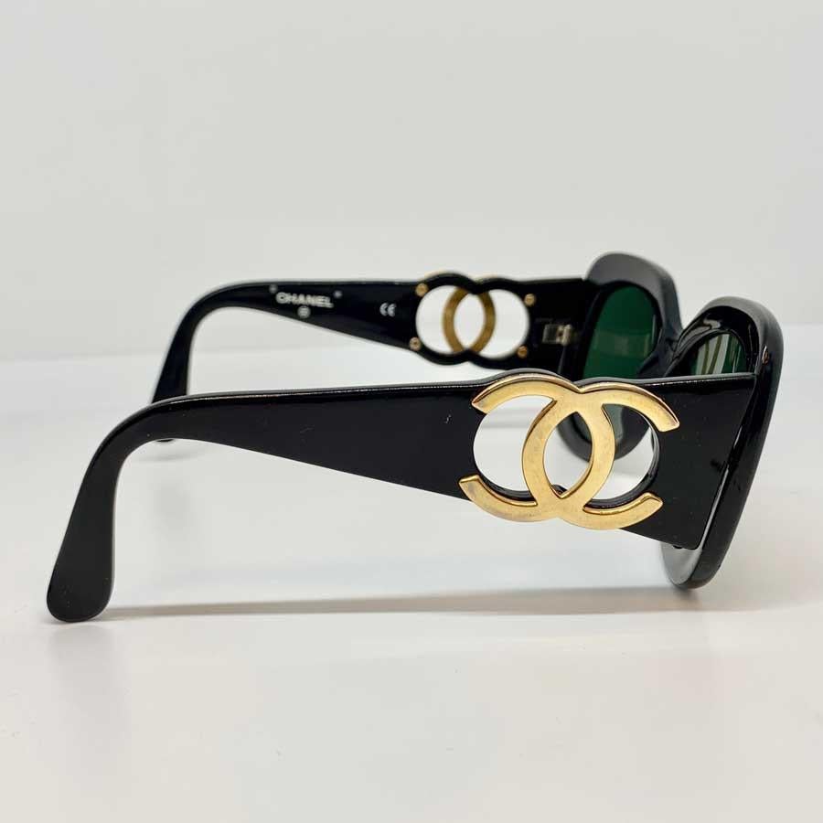 Collector's pair of sunglasses from Maison CHANEL. The black acetate frame and the lenses are dark. 
Each temple has a large openwork gold metal CC logo.
Mythical sunglasses from the Fall / Winter 1995 Collection.
It is a fairly covering model at