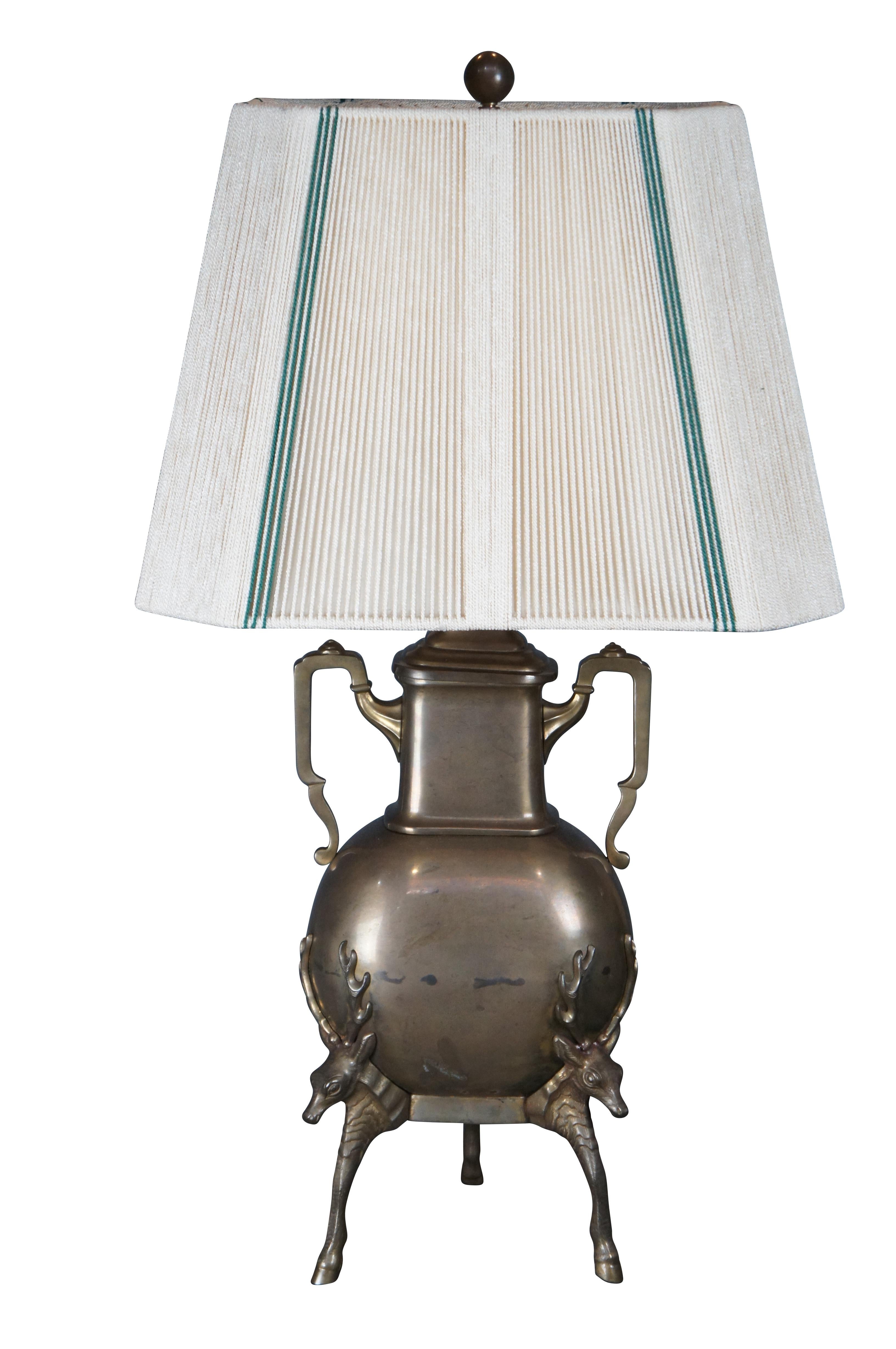 Chapman Industries brass urn shaped lamp with Stag / Elk tripod hoof footed base. Circa 1986. Includes an impressive green and white striped shade with cotton woven strings.

Dimensions:
13