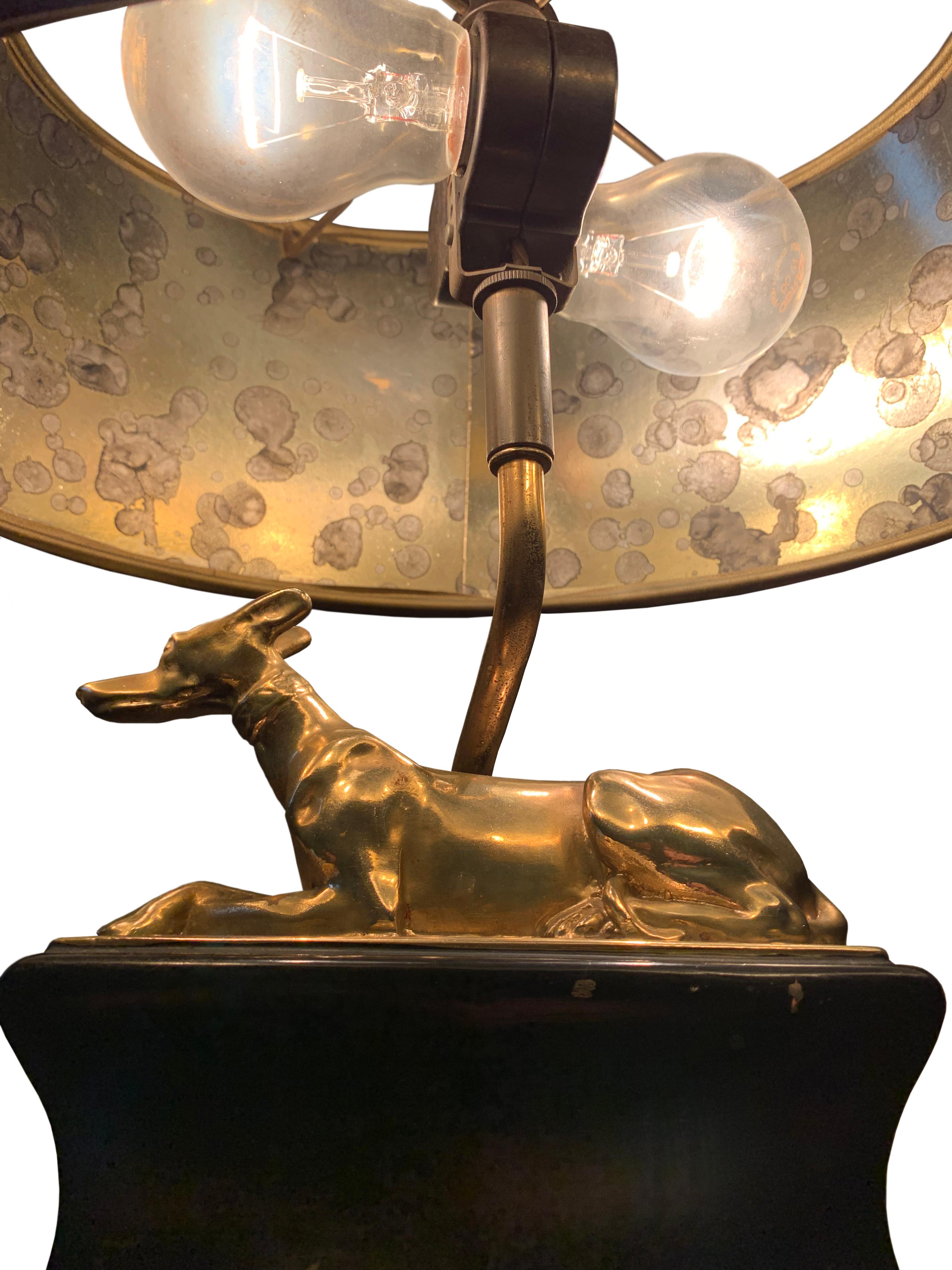 Adorable vintage brass Chapman Whippet lamp on a pedestal of books desk lamp. retaining it's original black parchment shade with gold tortoise lining and finial. 

The lamp has some chips to books, and mild patination to the whippet dog. The