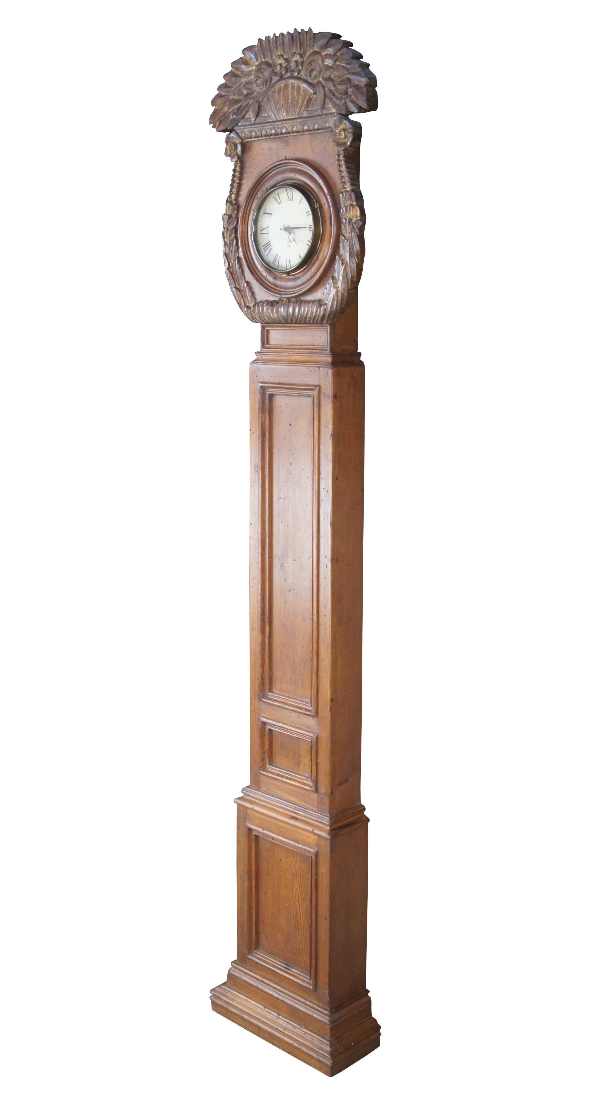 Gustavian inspired longcase clock by Chapman, circa last quarter 20th century. Made from distressed pine with a diminutive long paneled case. The round face of the clock is protected by a glass window and surrounded by acanthus leaf carvings. The