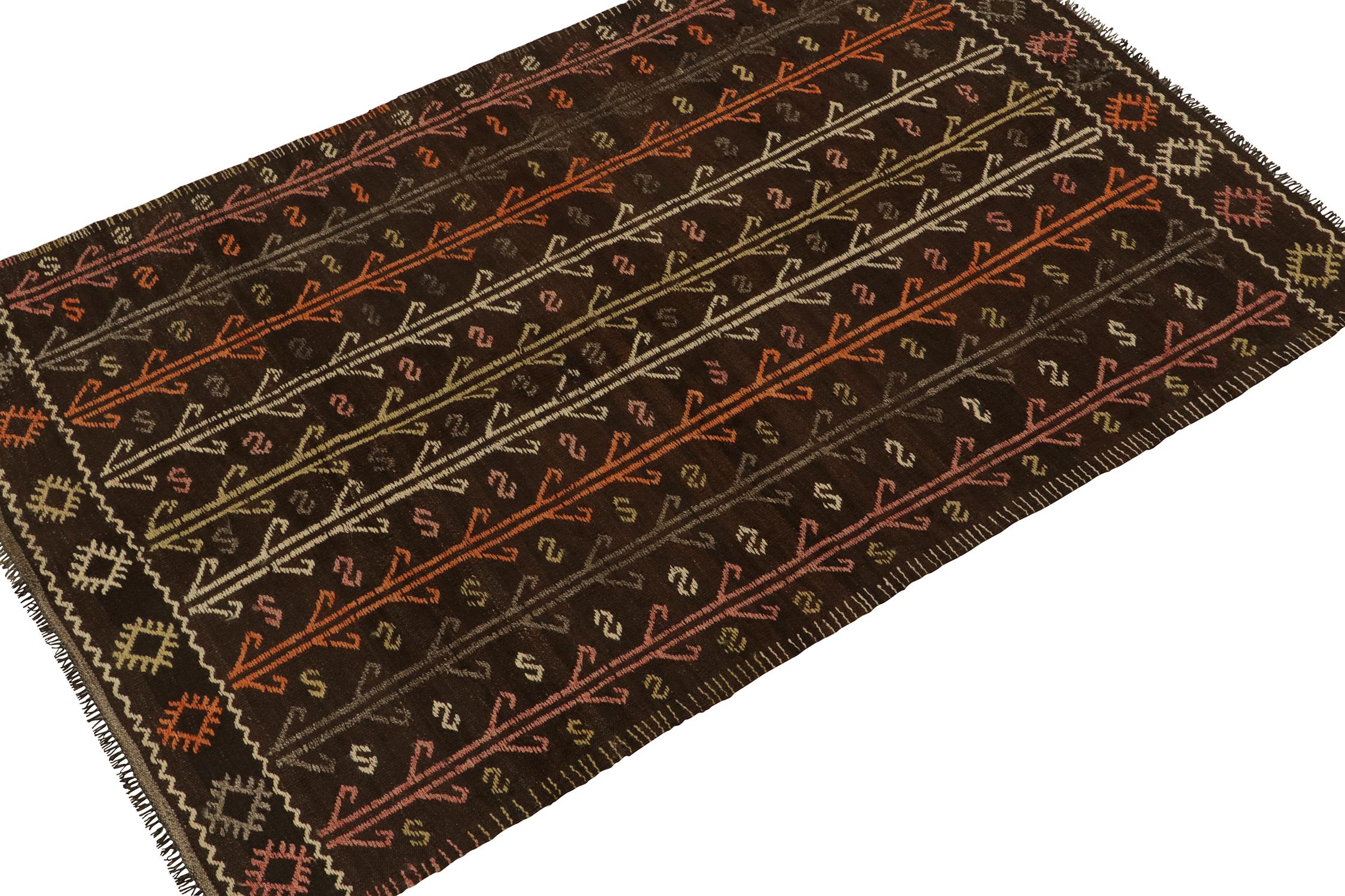 Originating from Turkey circa 1950-1960, a vintage Chaput style kilim rug connoting elaborate tribal sensibilities. Handwoven in wool, the piece exhibits an unusual play of vibrant embroidery atop a rich brown background seldom seen outside this and