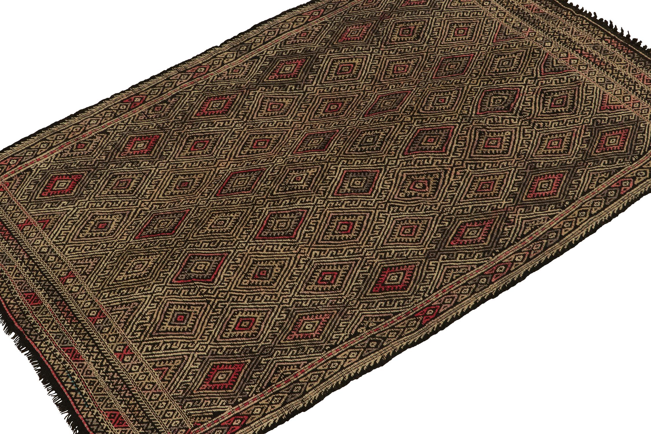 Originating from Turkey circa 1950-1960, a vintage Chaput style kilim rug connoting elaborate tribal sensibilities. Handwoven in wool, the piece exhibits an unusual play of vibrant red and beige-brown embroidery atop a black background seldom seen