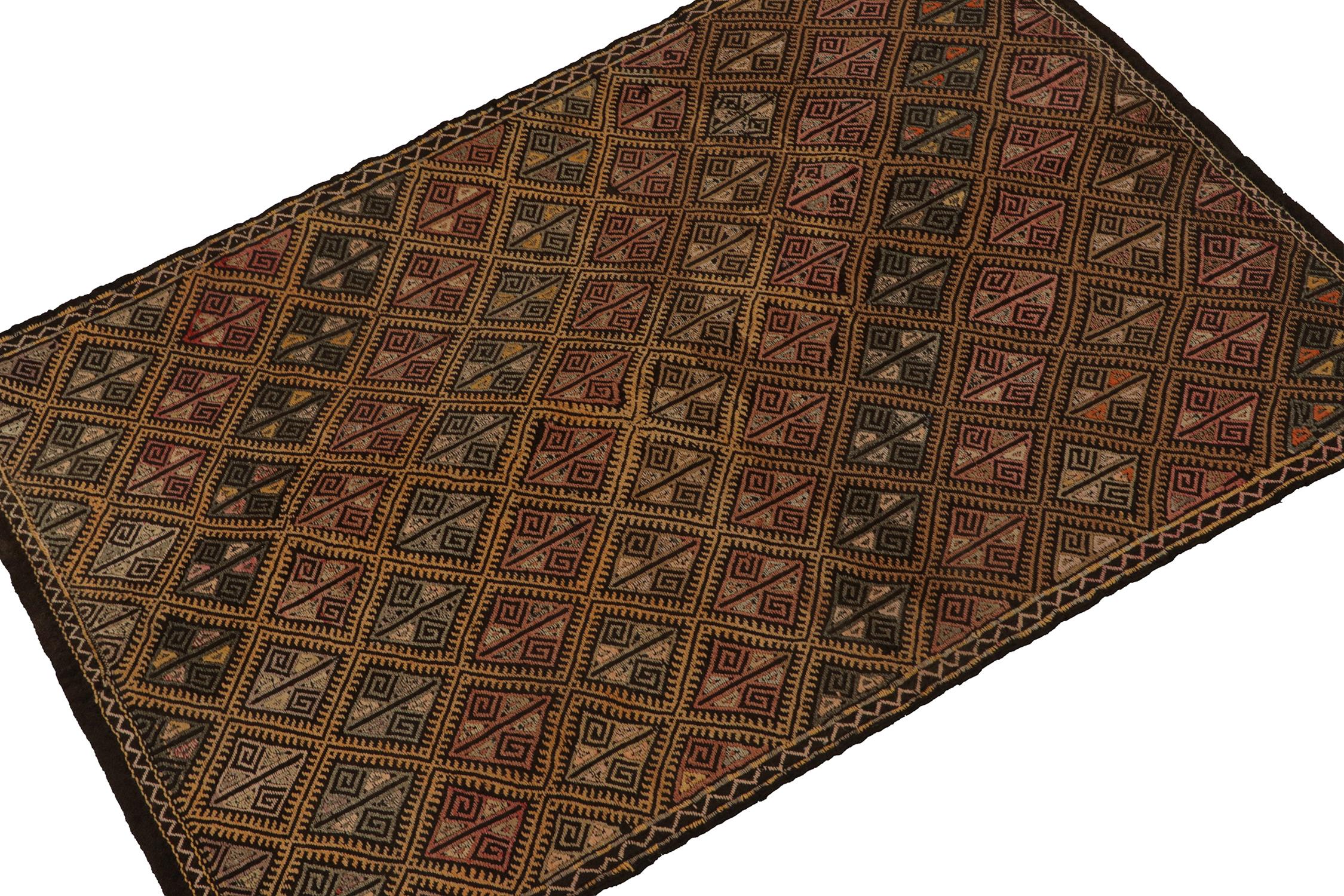 Originating from Turkey circa 1950-1960, a vintage Chaput style kilim rug connoting elaborate tribal sensibilities. Handwoven in wool, the piece exhibits an unusual play of vibrant embroidery atop a rich brown, trending-black background seldom seen