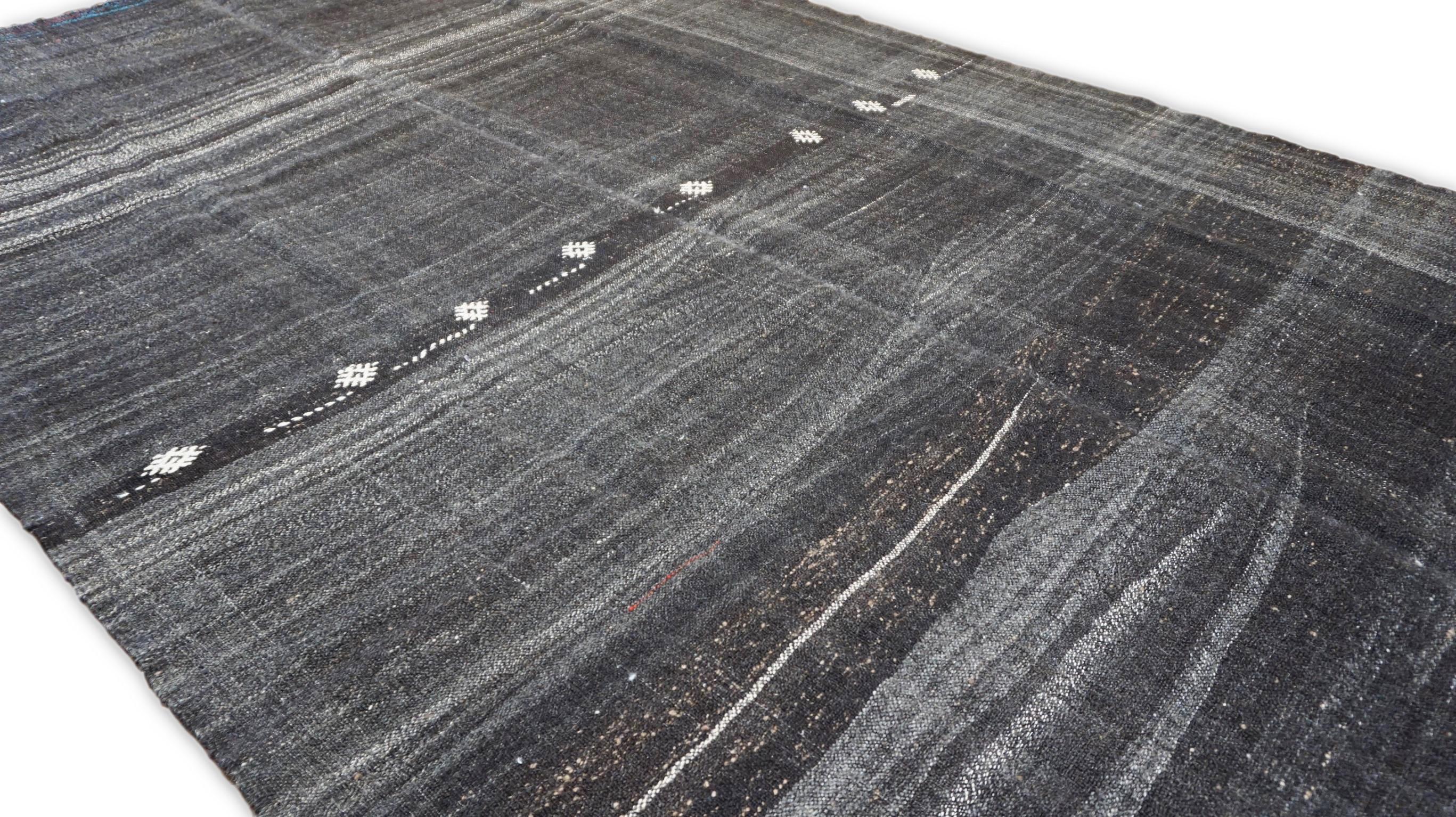 Ce tapis en laine tissé à plat et noué à la main incarne le minimalisme moderne avec un clin d'œil à l'artisanat traditionnel. Son design captivant présente de subtiles rayures horizontales dans des tons anthracite, gris, tan et ivoire, créant un