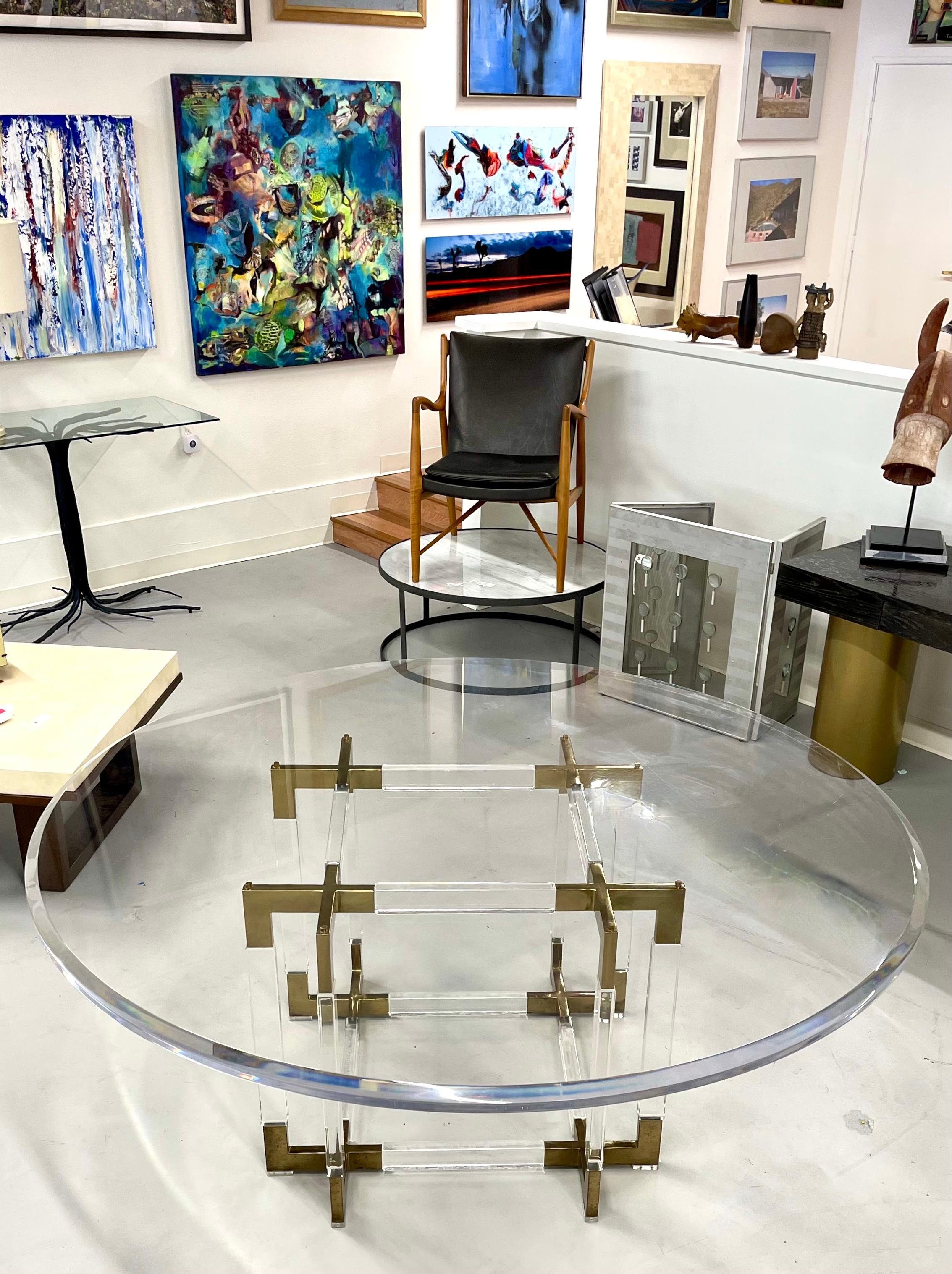 A vintage 1970's metric line Lucite and brass dining table by Charles Hollis Jones. This table features a beveled edge 72 inch diameter thick lucite top. The table is dining height at 29.75 inches. The base is in good age appropriate condition,