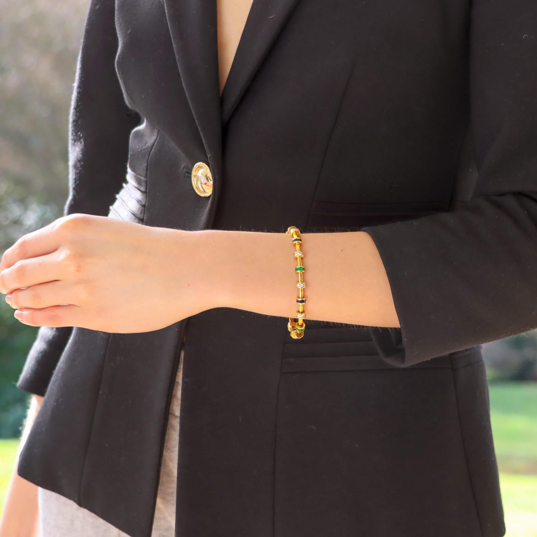 An extremely beautiful vintage Charles Krypell diamond, sapphire and emerald bracelet set in 18k yellow gold.

The bracelet is composed of exactly 19 gem set links, connected together by an articulated gold panel. Each link is set with either round