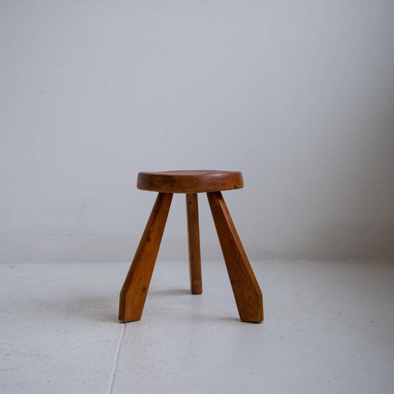 Iconic Les Arcs dark pine tripod by Charlotte Perriand from France. Bulky legs supported by a curved seat, this stool is expressive of the French designer. This rare stool has a perfect patinated dark pine, exceptional as an accent piece in any