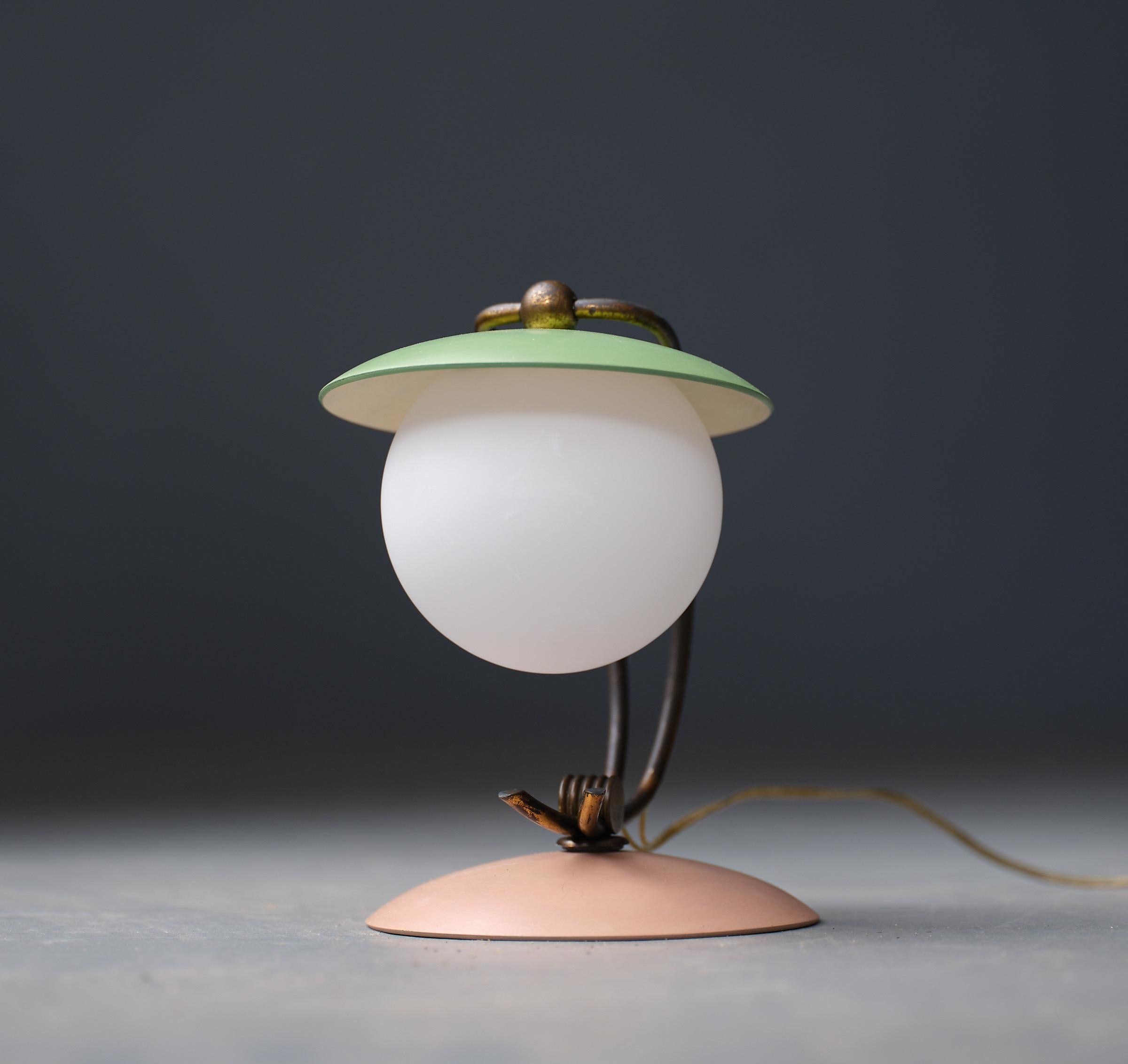 Presenting a delightful 1950s Italian table lamp, a testament to the timeless elegance and innovation of mid-century design. This piece beautifully marries aged brass with vibrant enamel accents in pink and green, capturing the playful yet