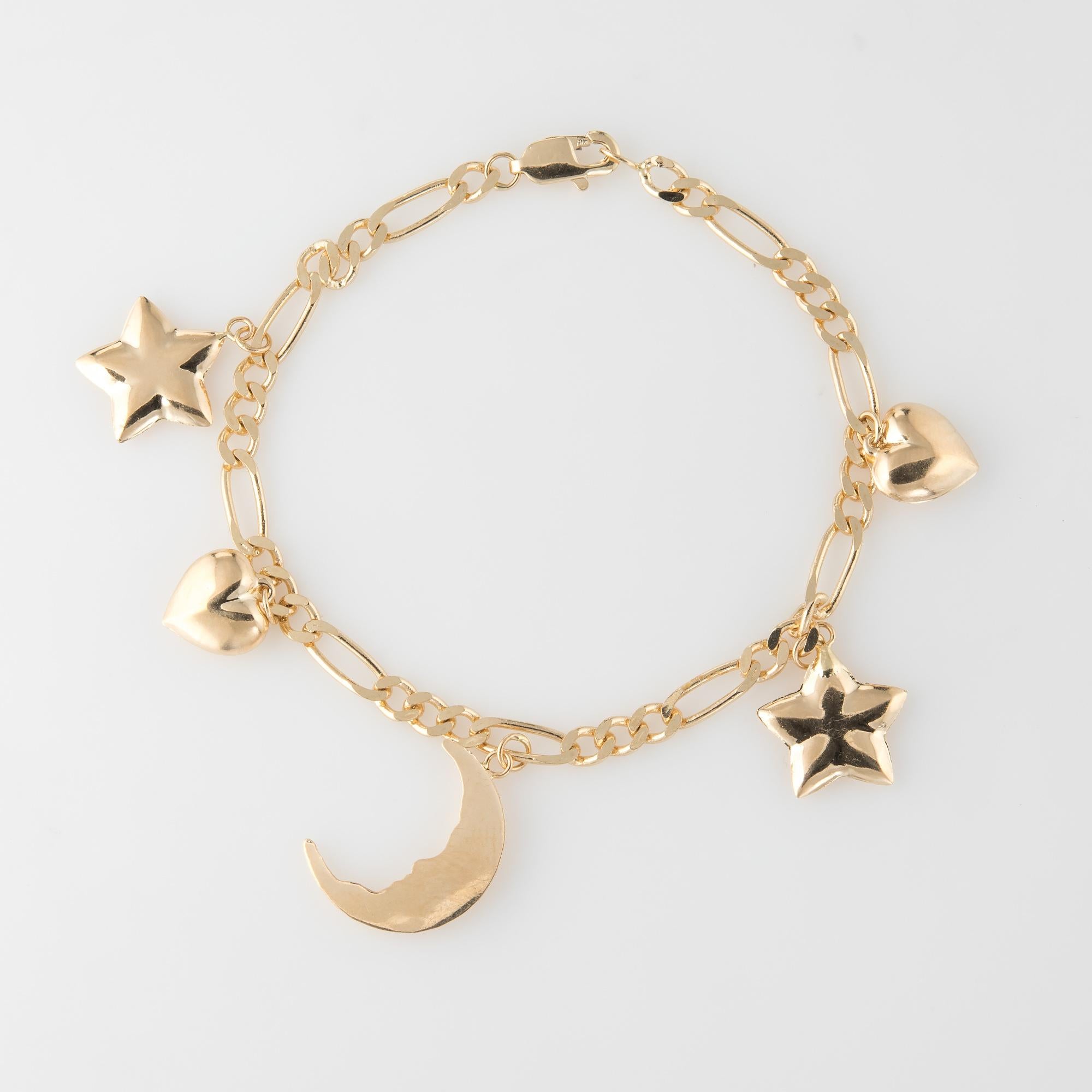 Stylish and finely detailed vintage celestial themed charm bracelet, crafted in 14 karat yellow gold.  

The charm bracelet features five charms with a crescent moon (and moon face), heart and star. The hollow charms have a lightweight feel.  

The