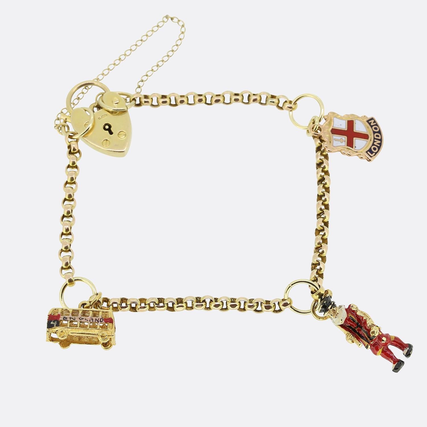 This is a vintage 9ct yellow gold belcher charm bracelet. The bracelet features three charms including an enamel bus, an enamel queens guard and an enamel United Kingdom flag charm. The chain is secured with an antique heart padlock clasp.