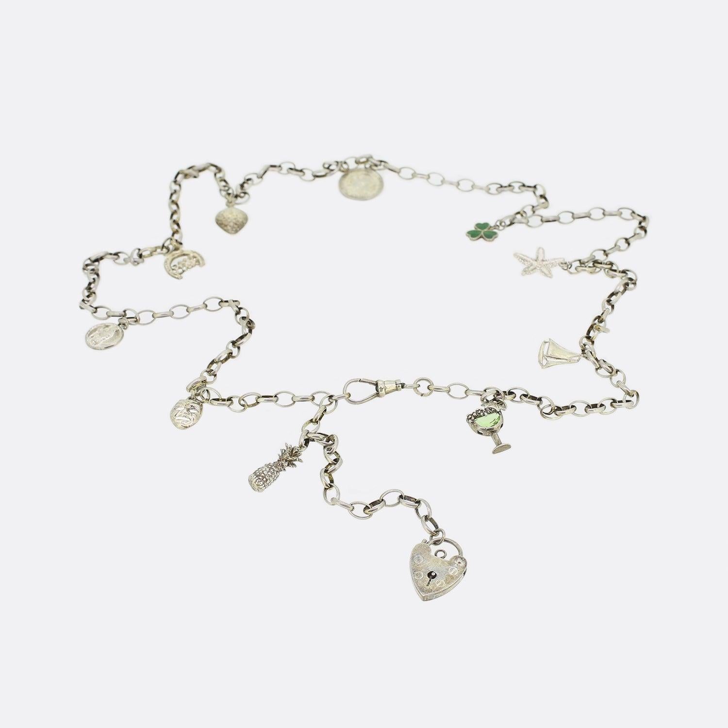 This is a vintage sterling silver belcher charm necklace. The necklace has charms attached throughout the chain including a starfish, a pineapple, a heart, an enamel clover and many others. The whole chain and charms have been made in sterling