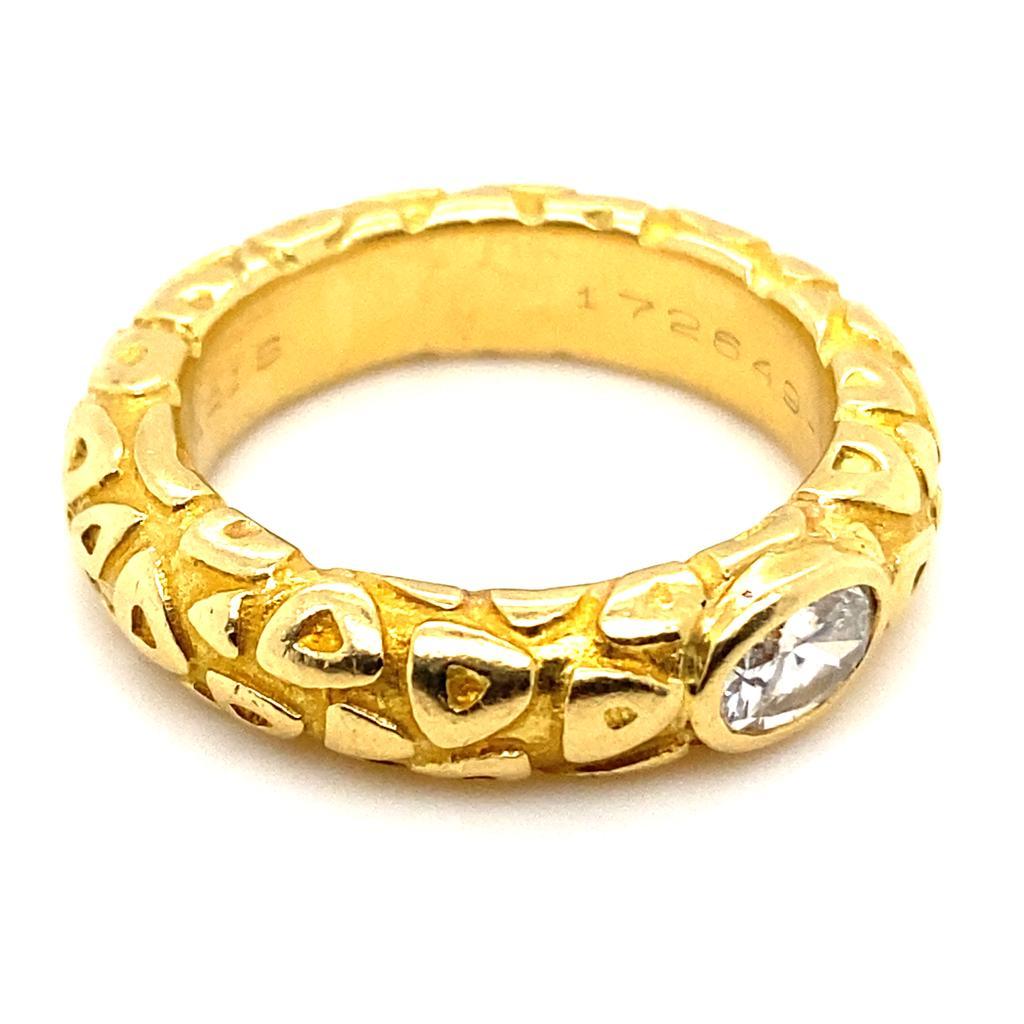 A vintage Chaumet diamond 18 karat yellow gold ring, circa 1960.

This ring features a rounded edge and a textured polished and matt finished gold cut-out design, reminiscent of snake skin.
A bezel set oval brilliant cut diamond of 0.50 carats