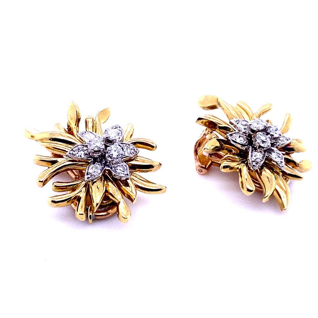 A pair of vintage Chaumet diamond flower earrings in 18 karat yellow and white gold, circa 1960.

Each clip of stylised floral design is set with grain and claw set round brilliant cut diamonds to its white gold centre with plain polished yellow