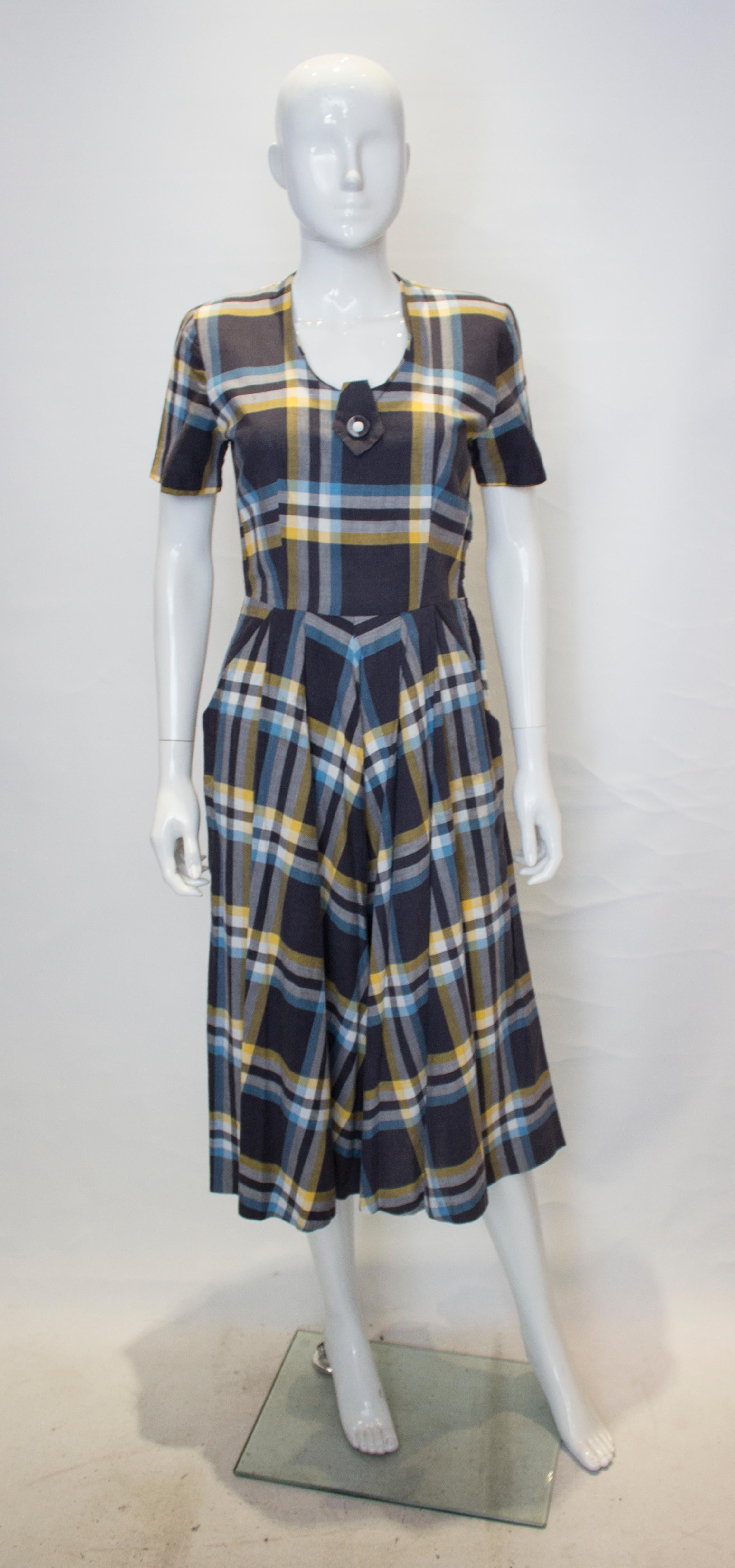 A chic check cotton vintage dress from the 1950s. The dress is in blue , yellow and white and has a scoop neckline,a side zip opening , and two pockets on the skirt. 