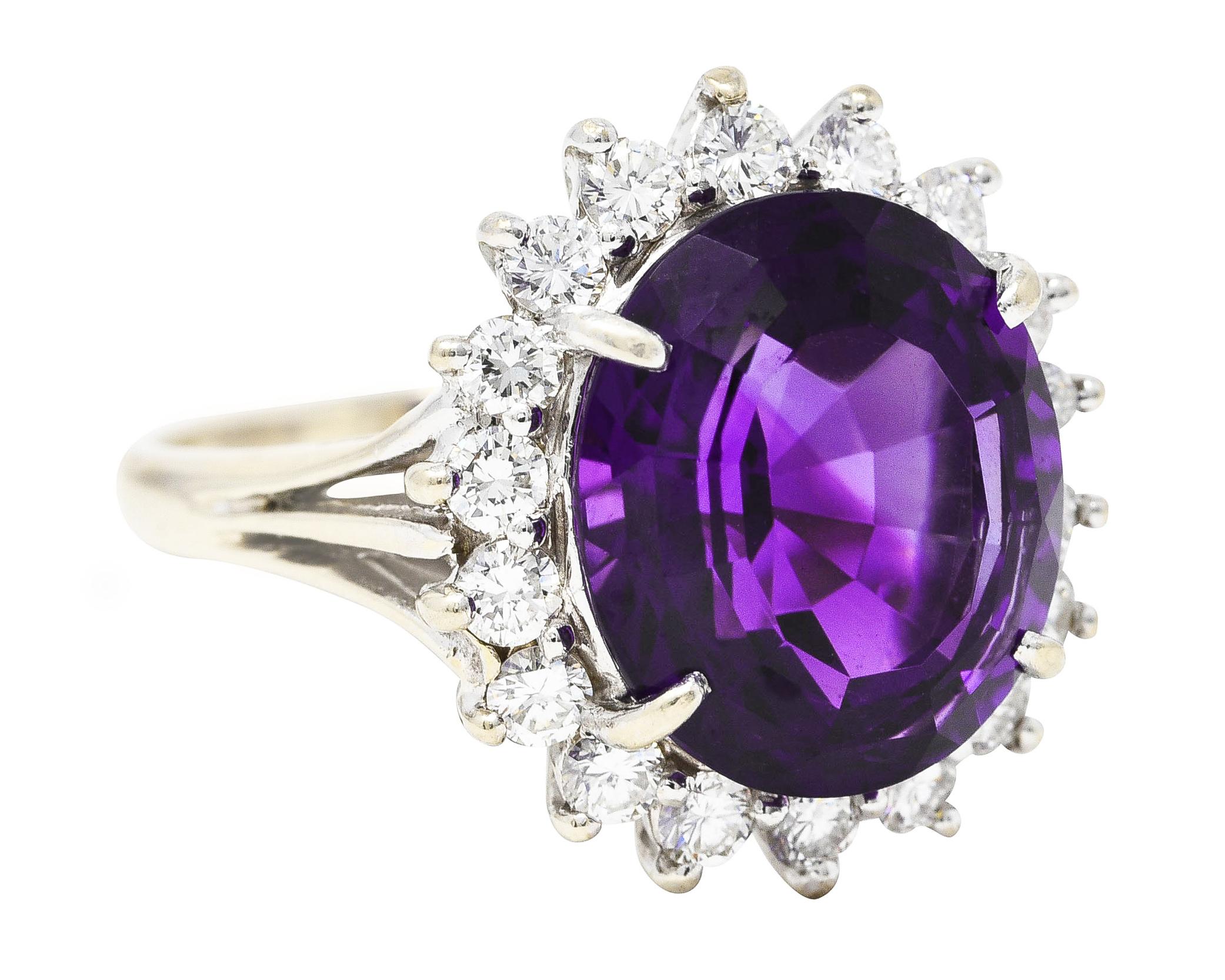 Cluster ring centers a checkerboard oval cut amethyst measuring 13.7 x 11.9 mm. Surrounded by a halo of round brilliant cut diamonds. Weighing collectively approximately 1.00 carat - G to I color with VS2 clarity. Completed by triple split cathedral