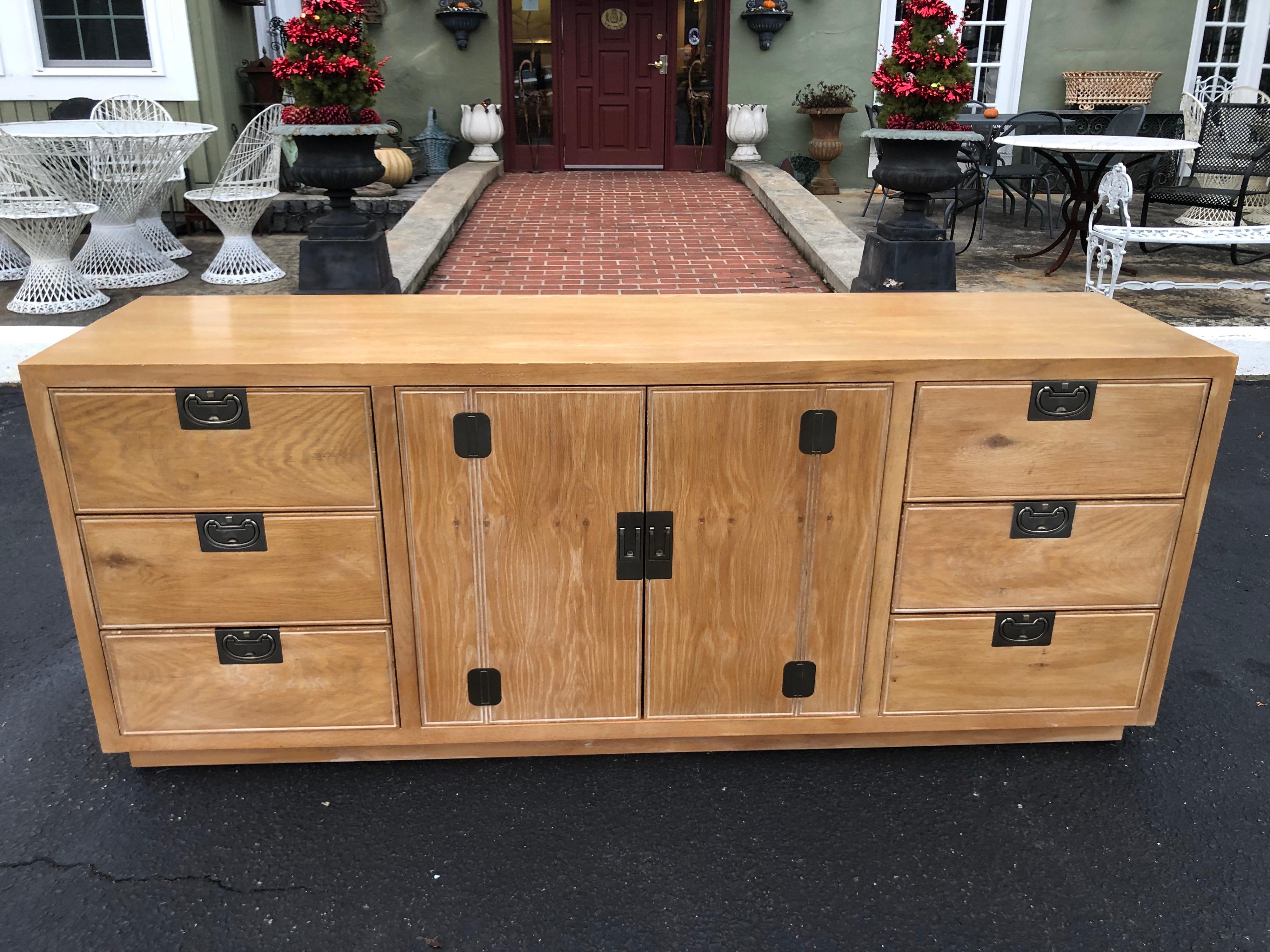 Vintage cherused campaign style oak dresser or credenza. Solid construction with original recessed metal campaign hardware. Three drawers one either side. Center doors open to a middle cabinet. If wanted we can have a custom shelf made as the