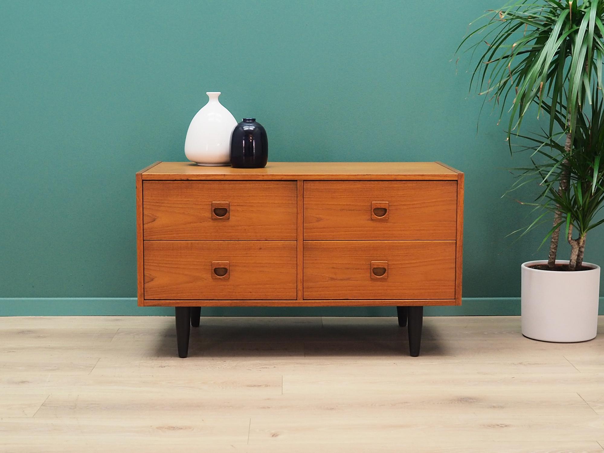 Brilliant chest of drawers from the 1960s-1970s. Minimalist form, Danish design. The furniture is covered with teak veneer, legs are made of solid teak wood. The chest has four symmetrical drawers. Preserved in good condition (small bruises and