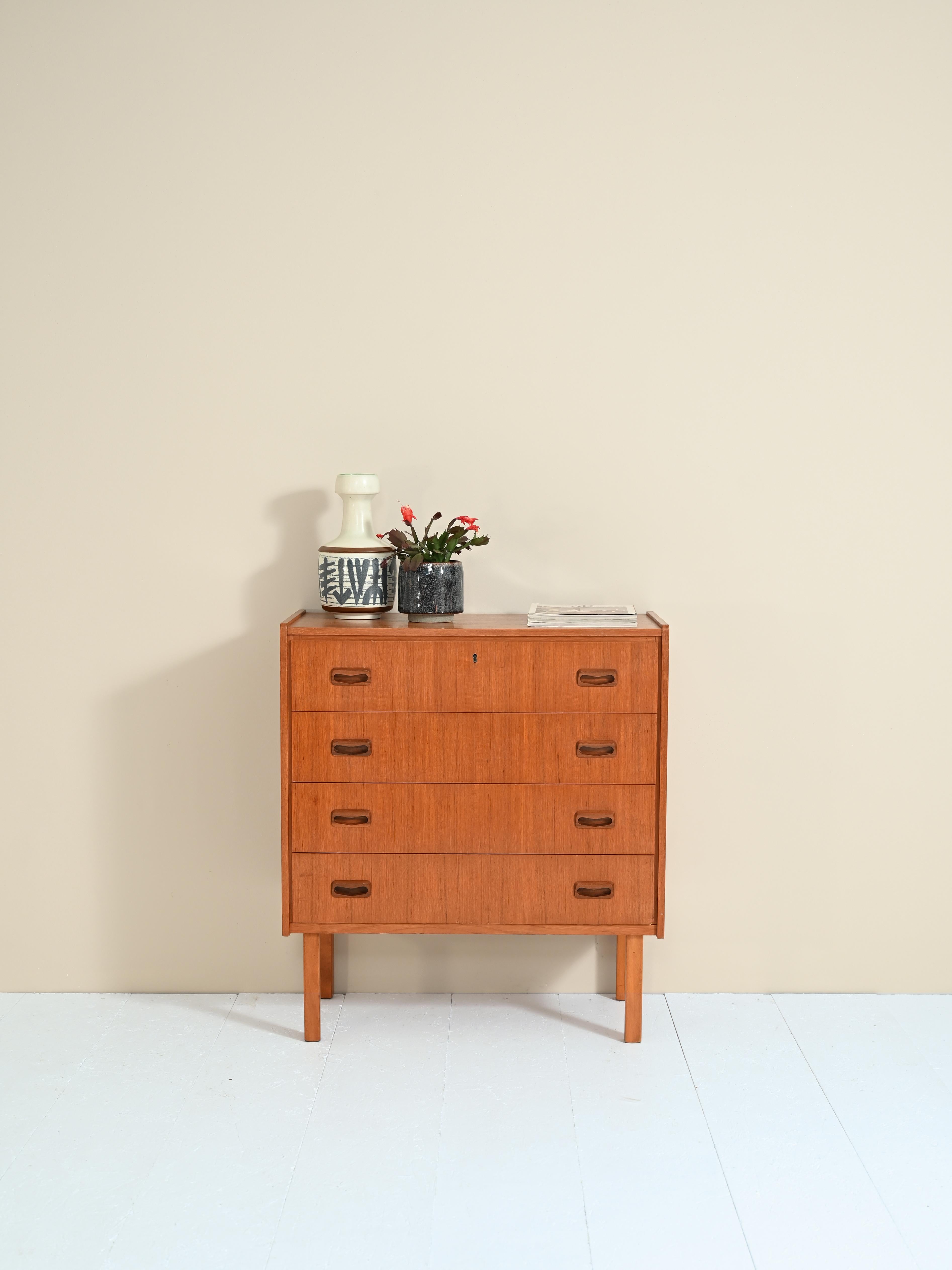 Vintage Scandinavian-made cabinet with four drawers equipped with lock and carved wooden handle.

The classic shapes and pronounced teak wood grain make this chest of drawers a timelessly beautiful piece of furniture.

Good vintage condition. A