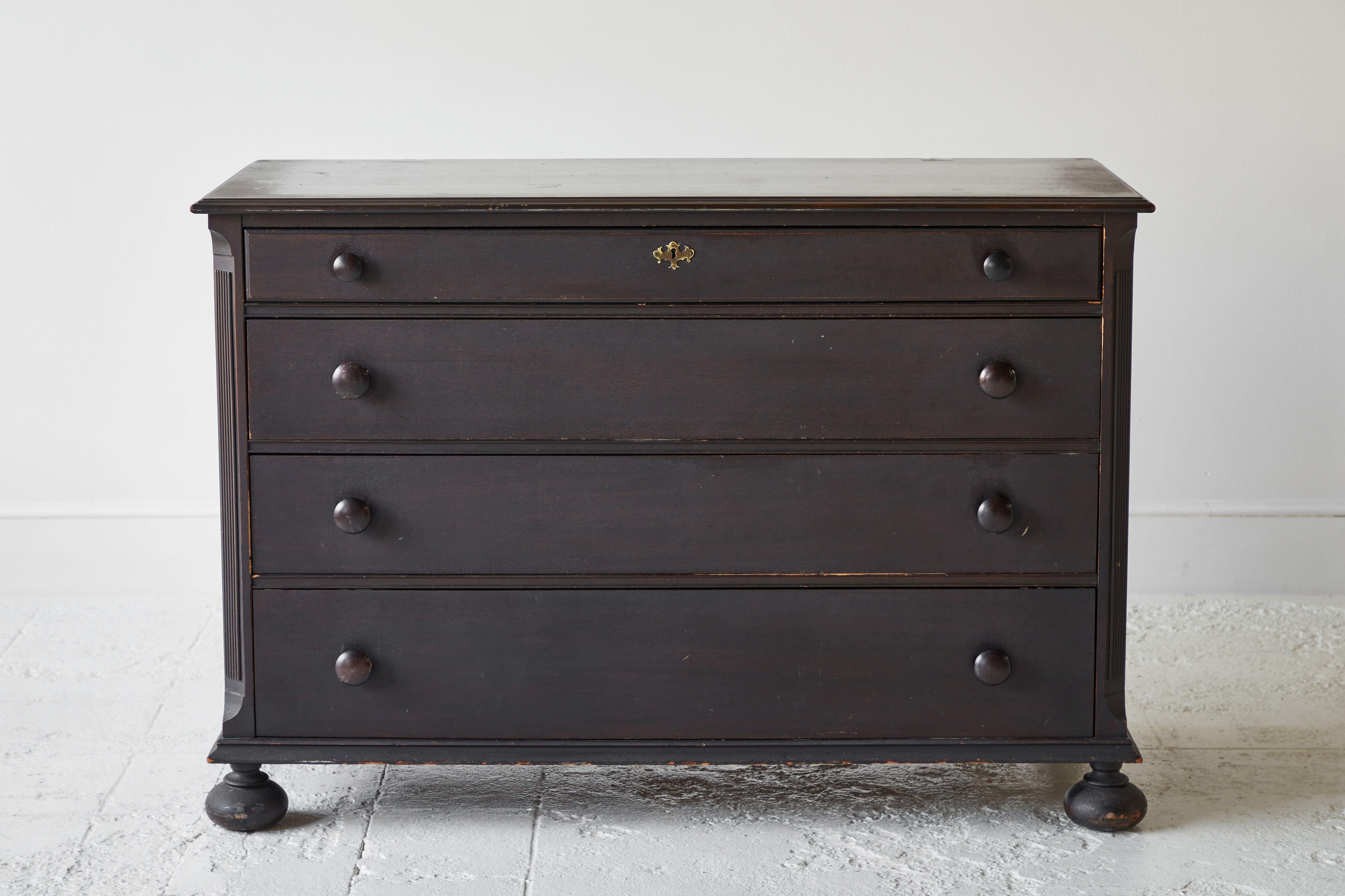 Vintage classic four-drawer chest of drawers with dark stained finish and round bun feet. Original hardware and original finish.
