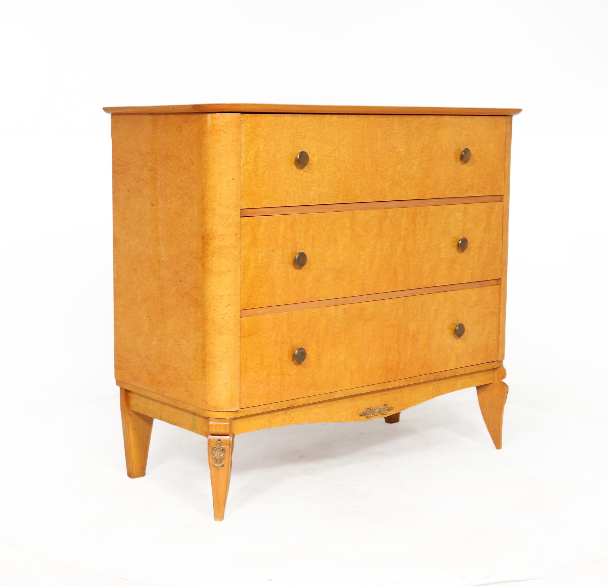 A very stylish vintage chest of drawers produced in France in the 1960’s using Karelian birch, having three long drawers with dovetail joint construction and gold printed handles, encased in a strong formed carcass with rounded Corners and standing