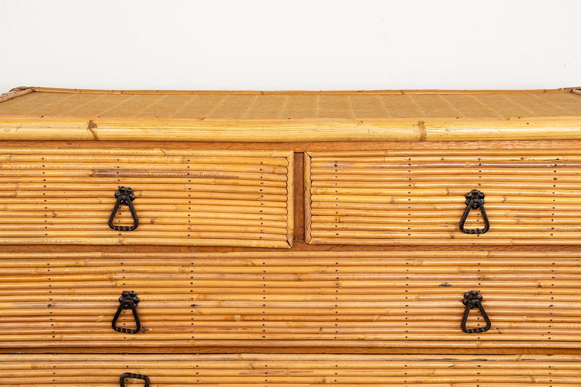 Splendida cassettiera in rattan con quattro cassetti su tre file e poggiata su gambe triangolari. Maniglie in ferro battuto nello stile delle creazioni di Audoux-Minet. Un mobile raffinato, funzionale e altamente decorativo. Stile