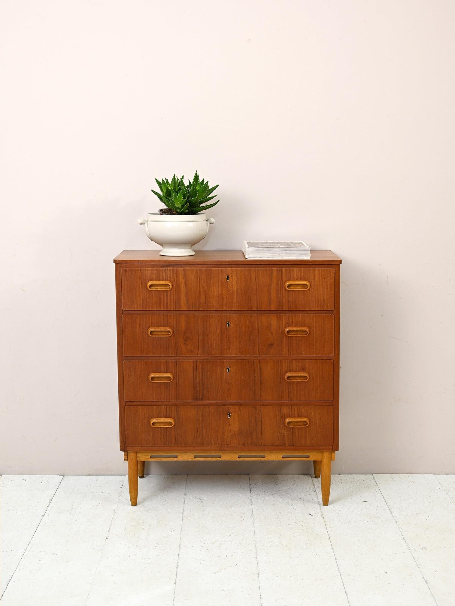 This chest of drawers with modern lines is distinguished by refined details, particularly the wood inlay present on the base. The legs and handle of the carved wooden drawers are made of light oak that stands out from the rest of the teak frame.
An