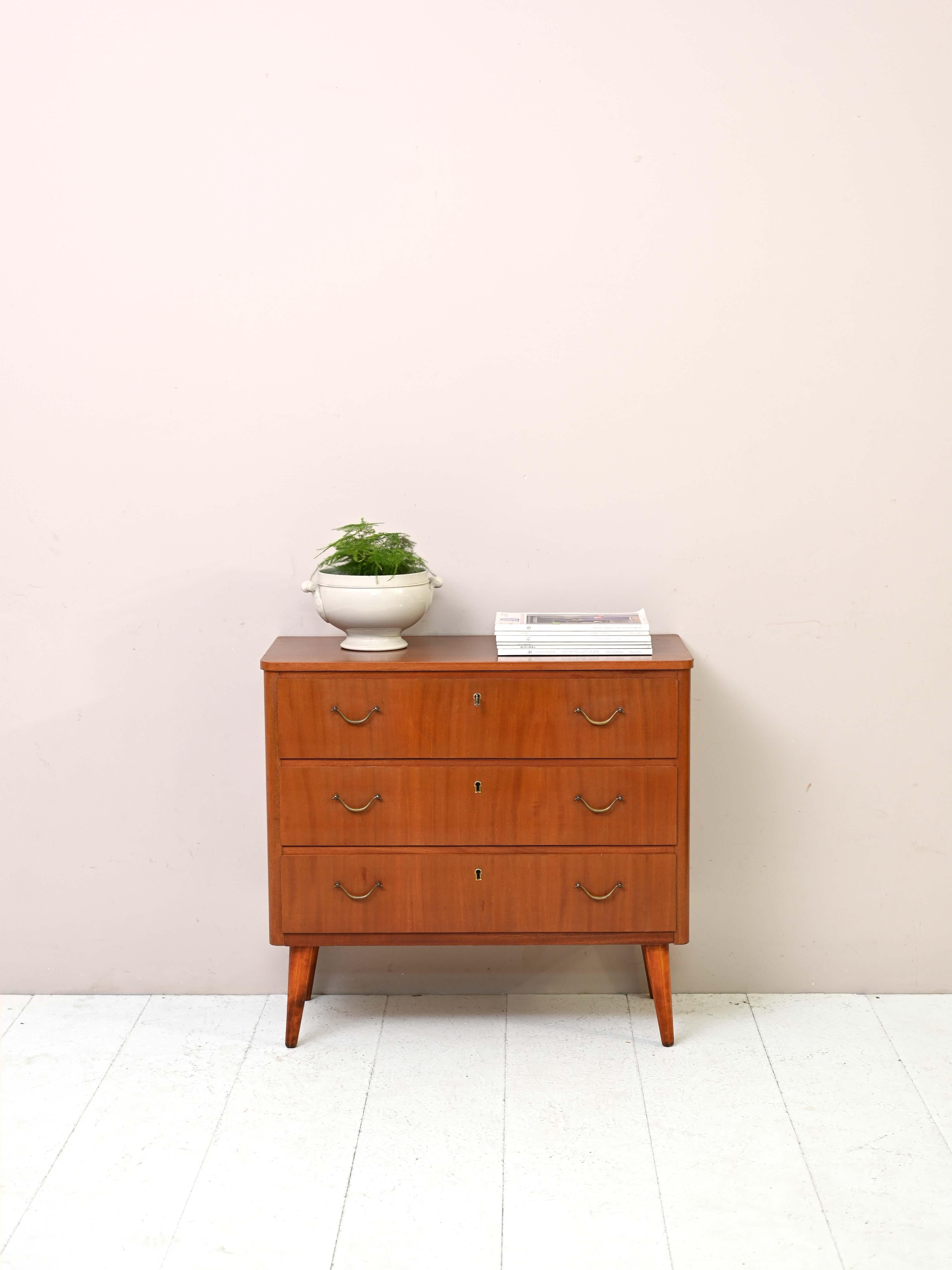 Scandinavian 1960s cabinet with drawers.

This retro-looking chest of drawers is distinguished by its details equipped with handles and a lock. The classic lines of the top with rounded edges and conical legs make it a piece of furniture with