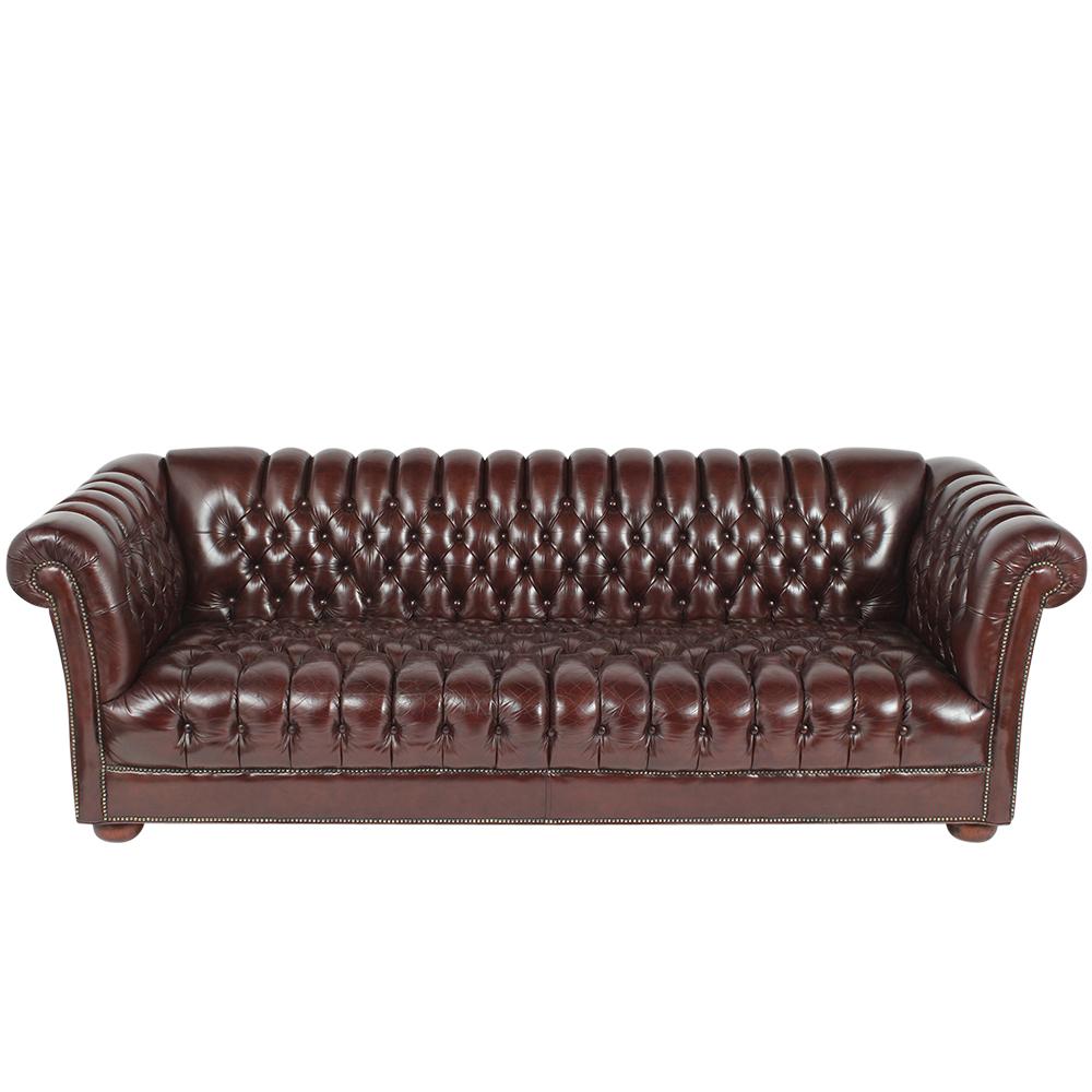 This amazing 1970s Chesterfield leather sofa has been newly restored and has dyed in a rich burgundy color with a wonderful patina finish. The sofa features scroll back/armrests, tufted seat design with brass nail details, and rest on rounded feet