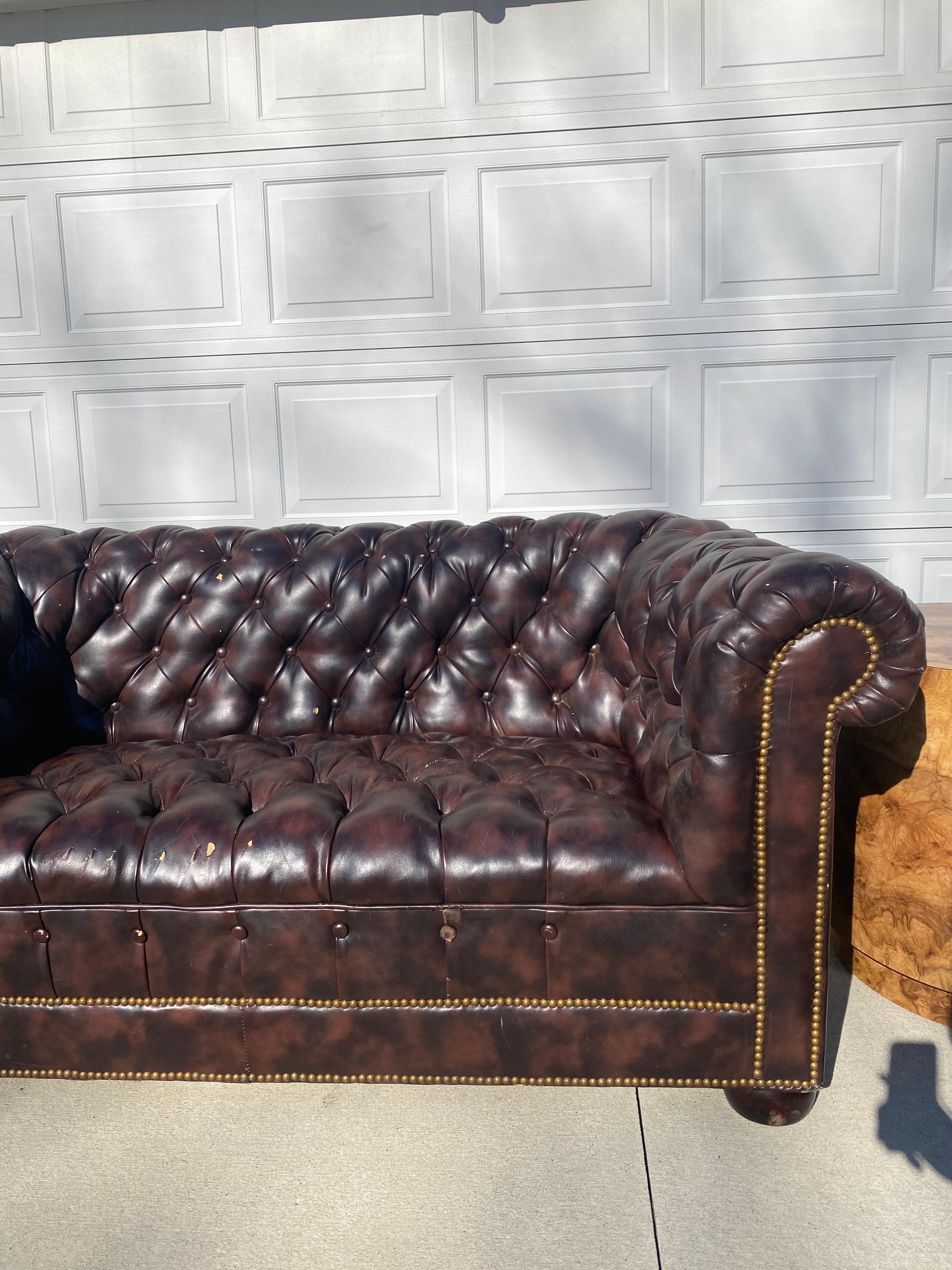 Chesterfield Sofa in Vegan Leather. This piece does need to be reupholstered. See photos. It is a beauty though, with some TLC, this will be a great addition to your home library, bar or any room in your home.