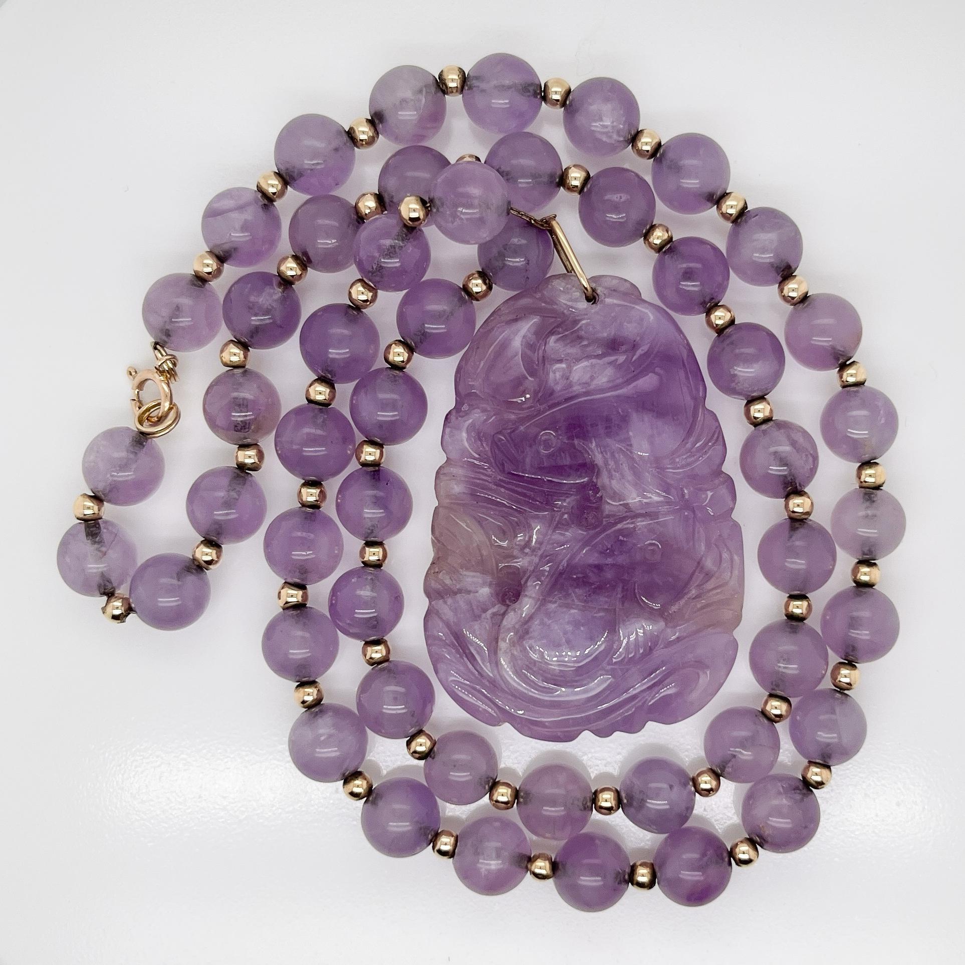 A very fine vintage Chinese 14k gold and purple jade pendant beaded necklace.

Comprising a large carved purple jade pendant and a beaded necklace.

The pendant has a depiction of koi fish on both sides. The necklace has alternating purple jade and