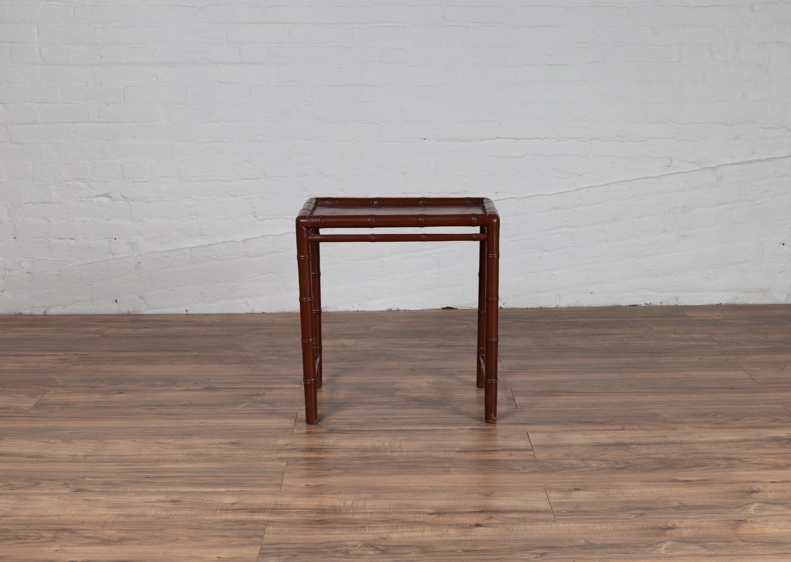 A Chinese vintage bamboo side table from the mid-20th century, with brownish patina. Born in China during the midcentury period, this unpretentious side table features a brown hued structure made of bamboo. Presenting a rectangular top with recessed