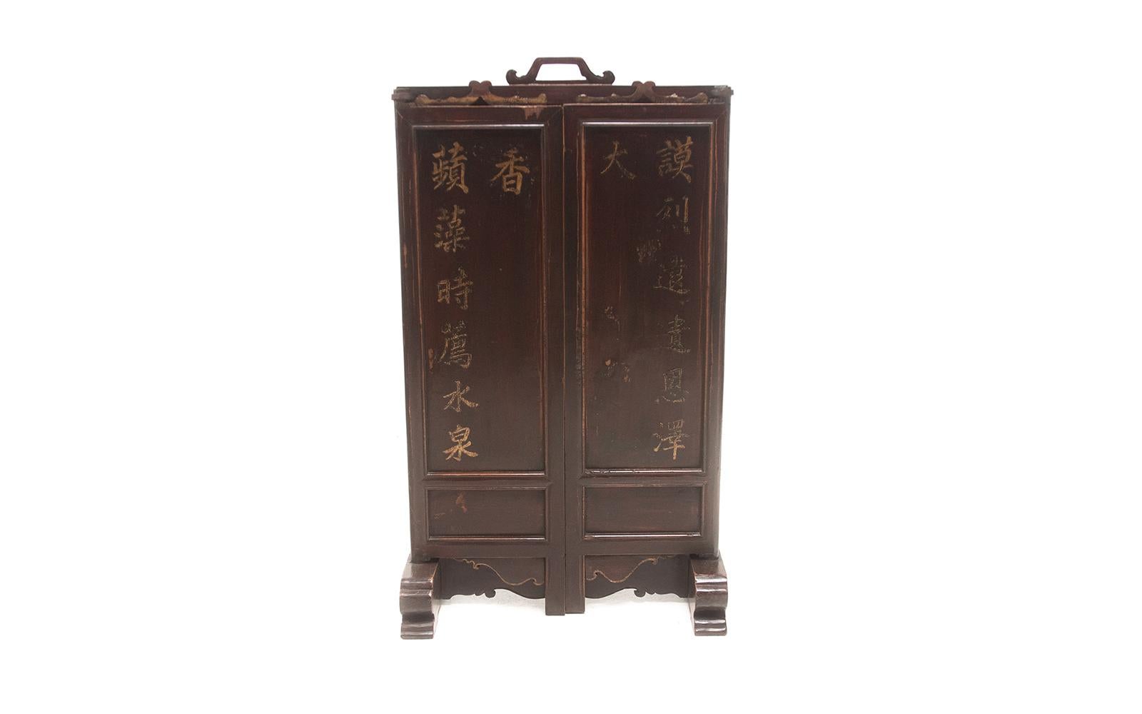 Early 20th century wood and lacquer Chinese ancestral folding table screen with inscriptions

A wood, cast iron lacquered Chinese ancestral folding table screen featuring inscriptions sits on sturdy feet. A wooden carved handle on the top to make