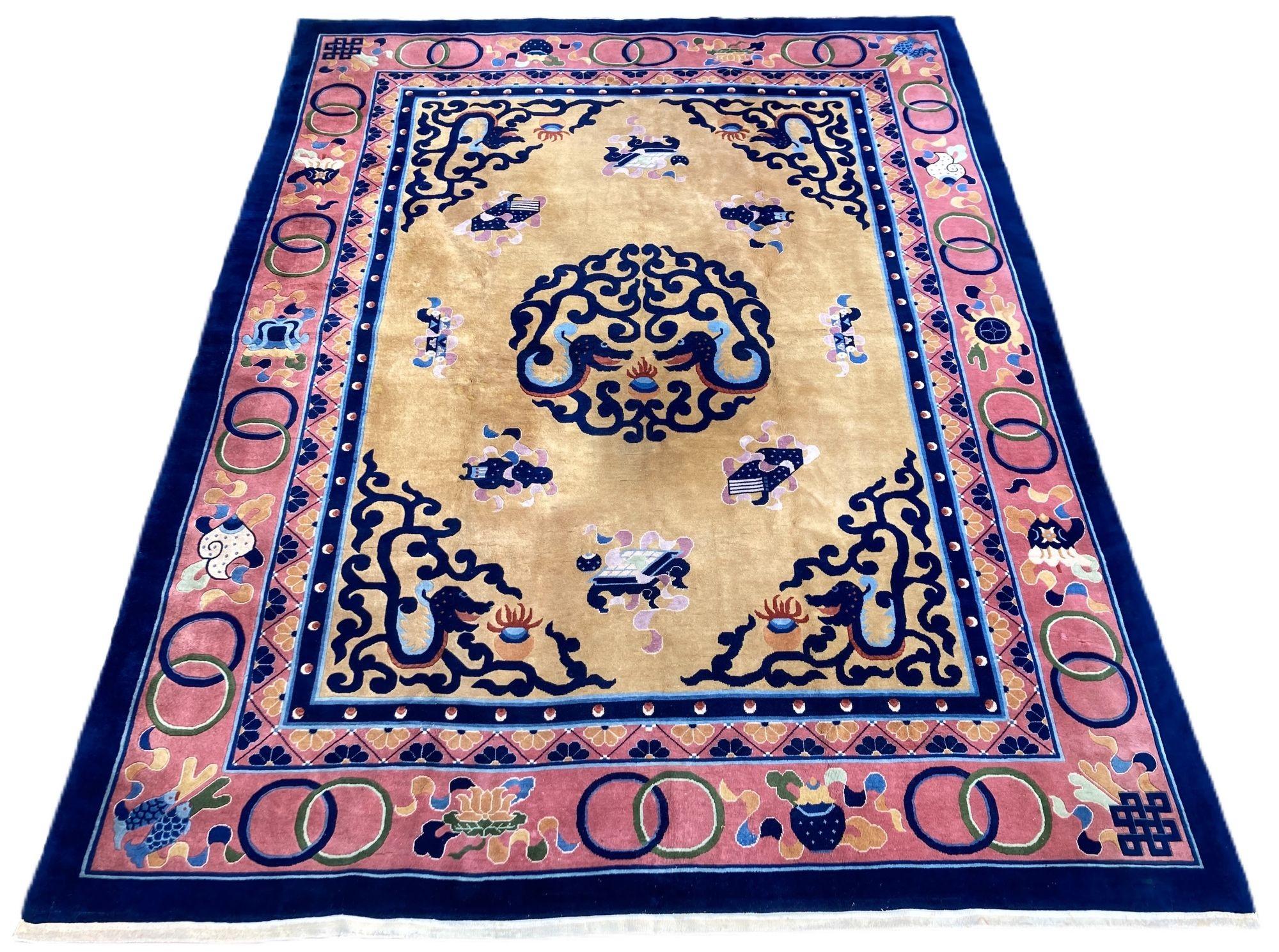 A lovely vintage Art Deco carpet, hand woven in China circa 1960 with a medallion of 2 duelling dragons surrounded by Buddhist symbols on a light gold field and salmon border. Note the dragons in the corner spandrels and the additional symbols in