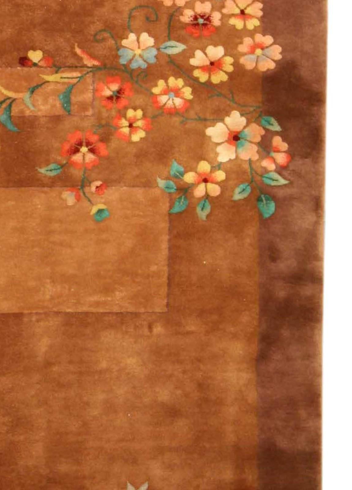 A second quarter of the 20th century Chinese Art Deco carpet, the asymmetrical field divided into solid stepped and rectangular forms in dusty rose, beige and brown with a few scattered flowering branches within an open brown border.