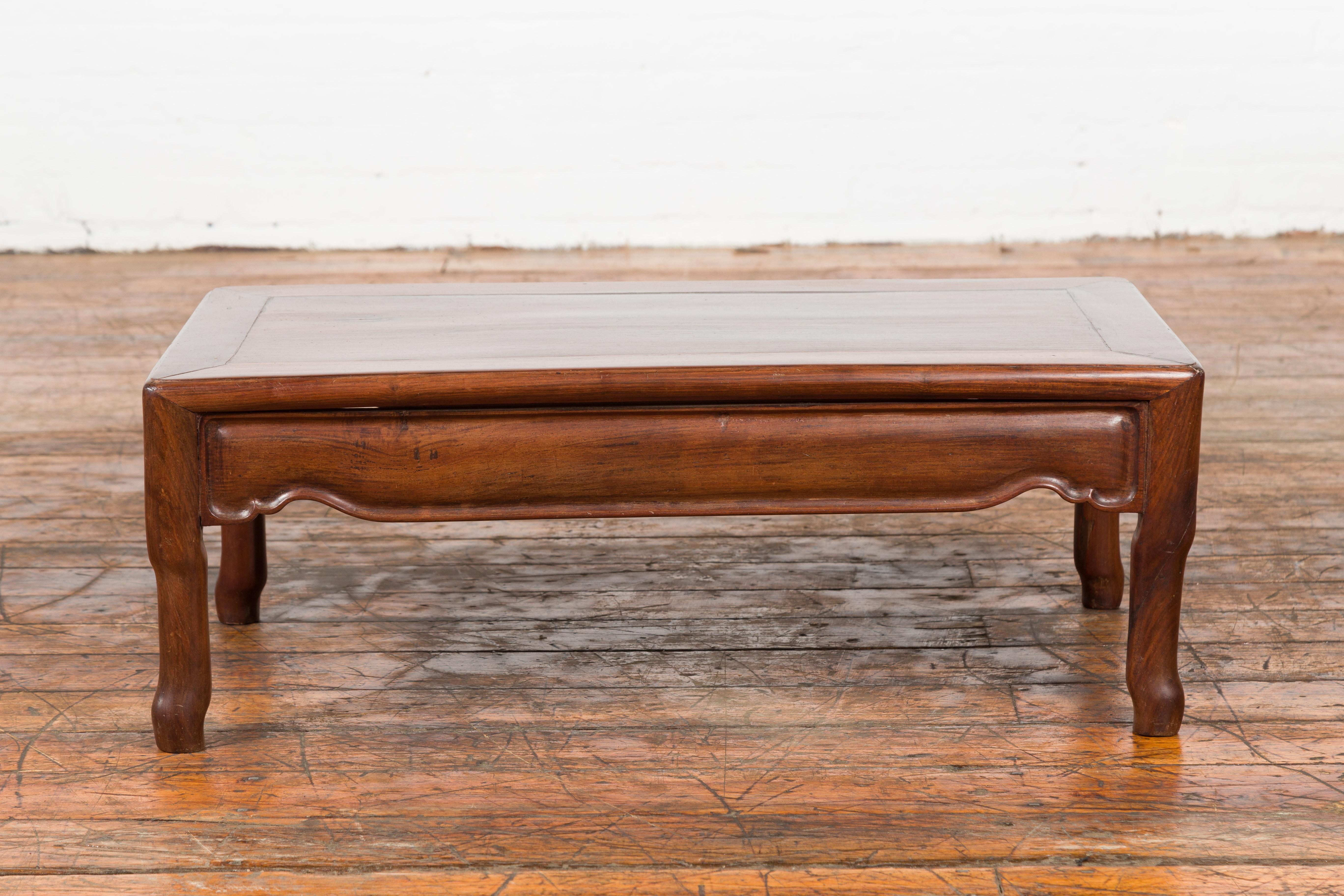 A vintage Chinese Art Deco style low prayer table from the 20th century, with carved apron. Created in China, this Art Deco style prayer table features a rectangular top with central board, sitting above an apron carved on all side. Raised on four