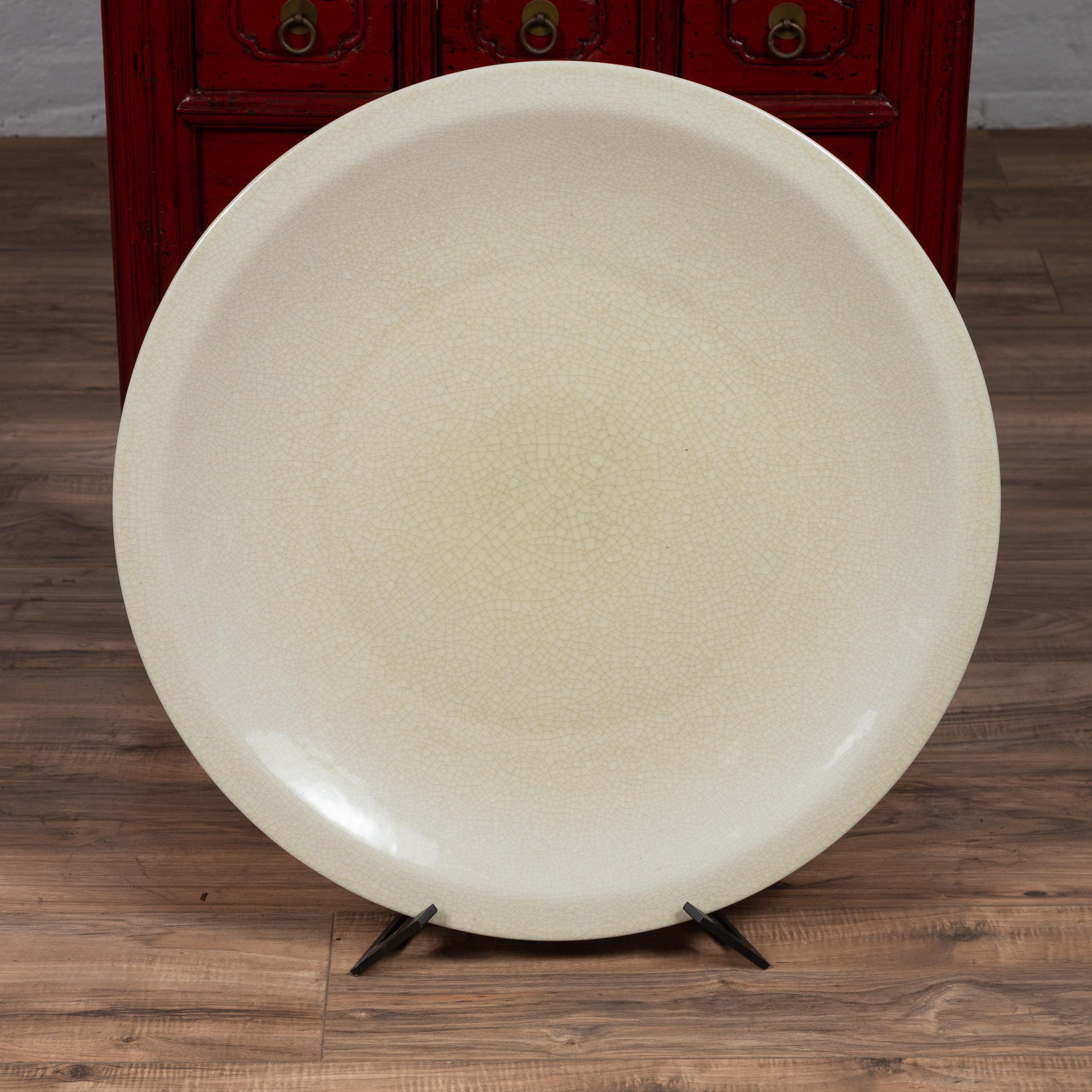 A Chinese vintage beige ceramic charger plate from the second half of the 20th century. We have two beige chargers available, priced and sold individually. Born in China during the 1980s, this elegant charger plate features a charming beige color
