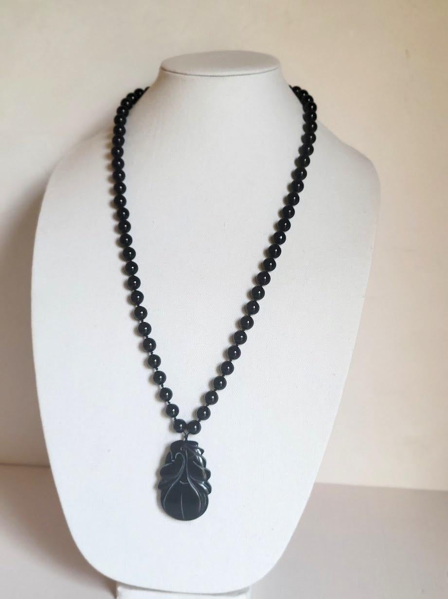 A vintage estate natural black Chinese agate carved pendant and bead necklace.
The agate pendant is cut in fruit design and is strung on black silk cotton with high-quality agate beads. The carved agate pendant is a peach and leaf design that