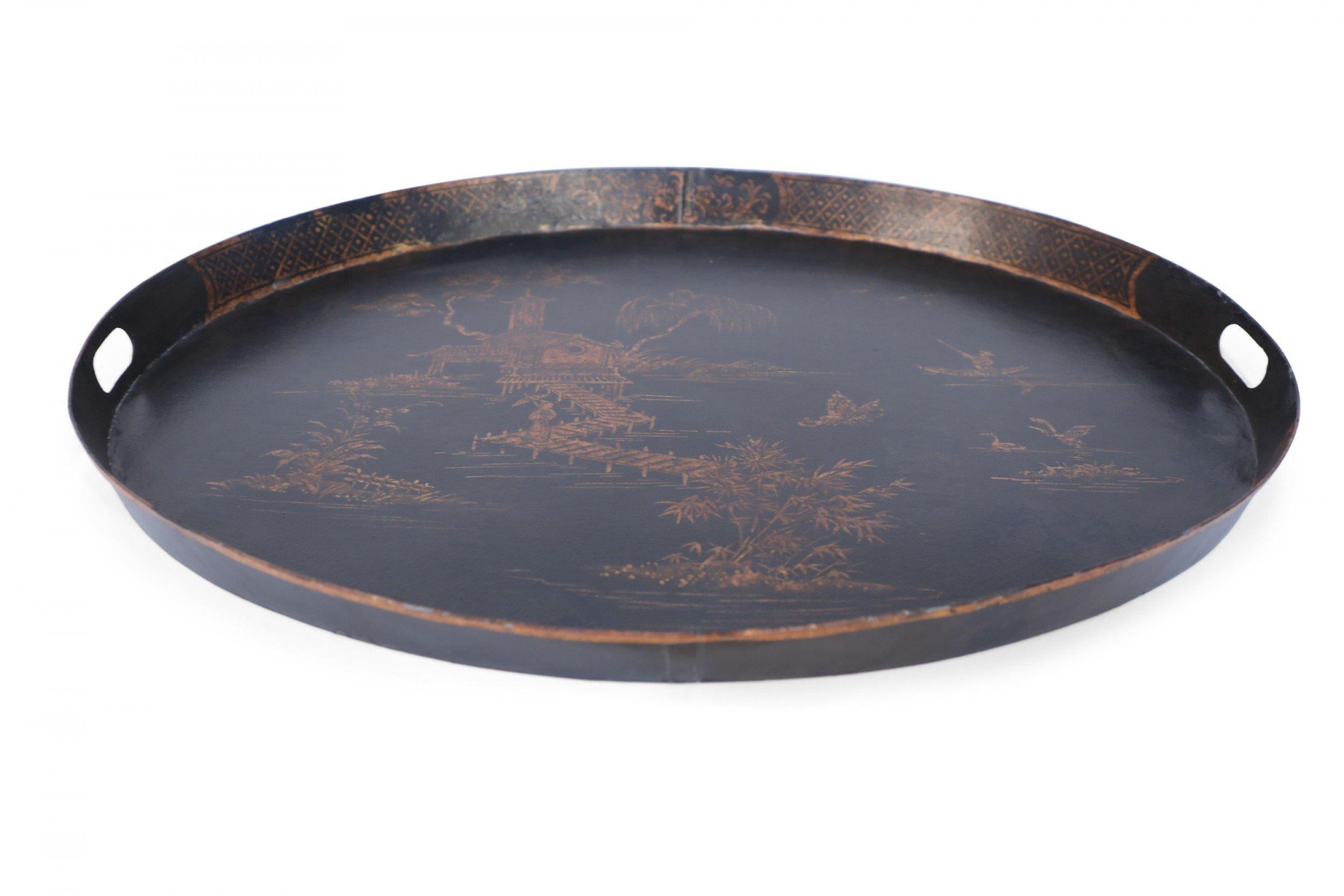 Vintage Chinese tole serving tray with a painted gold design of a lake scene on a black background with a shallow lip with two cut out handles.
 