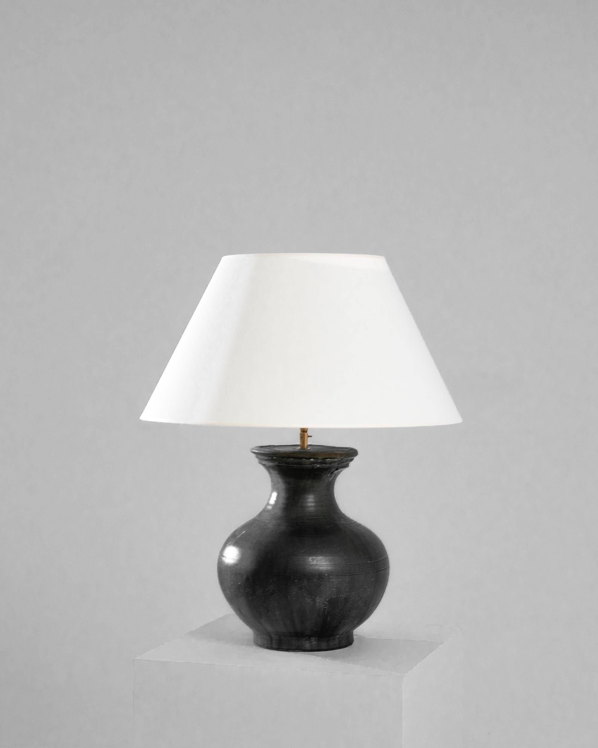 An exceptional find to inspire your collection. This vintage Chinese vase has been adapted into a beautiful table lamp. Polished brass meets the charcoal black glaze, enlightening your space with an uncompromising contrast. The textured glaze,