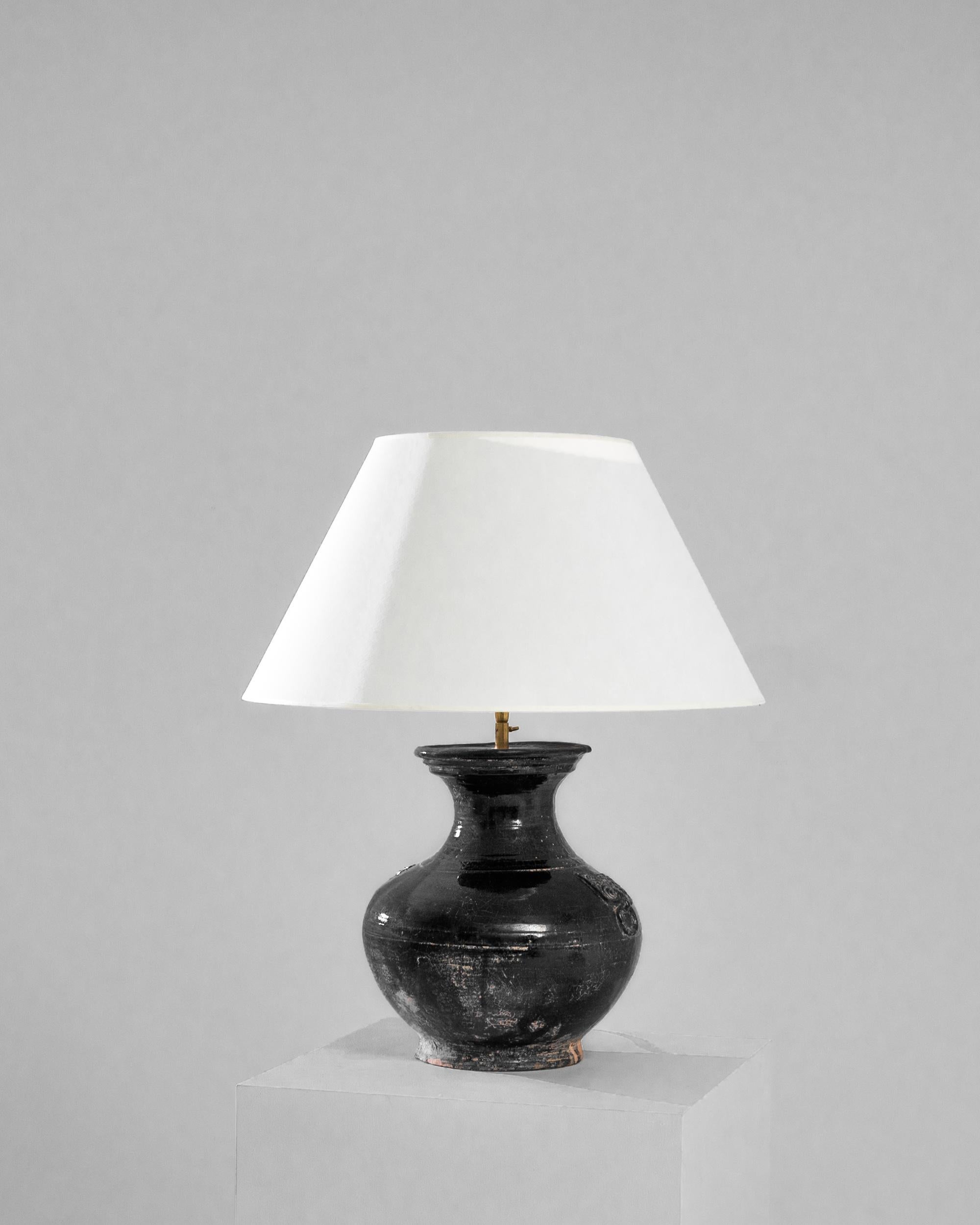 An exceptional find to inspire your collection. This vintage Chinese vase has been adapted into a beautiful table lamp. Polished brass meets the charcoal black glaze, enlightening your space with an uncompromising contrast. The textured glaze,