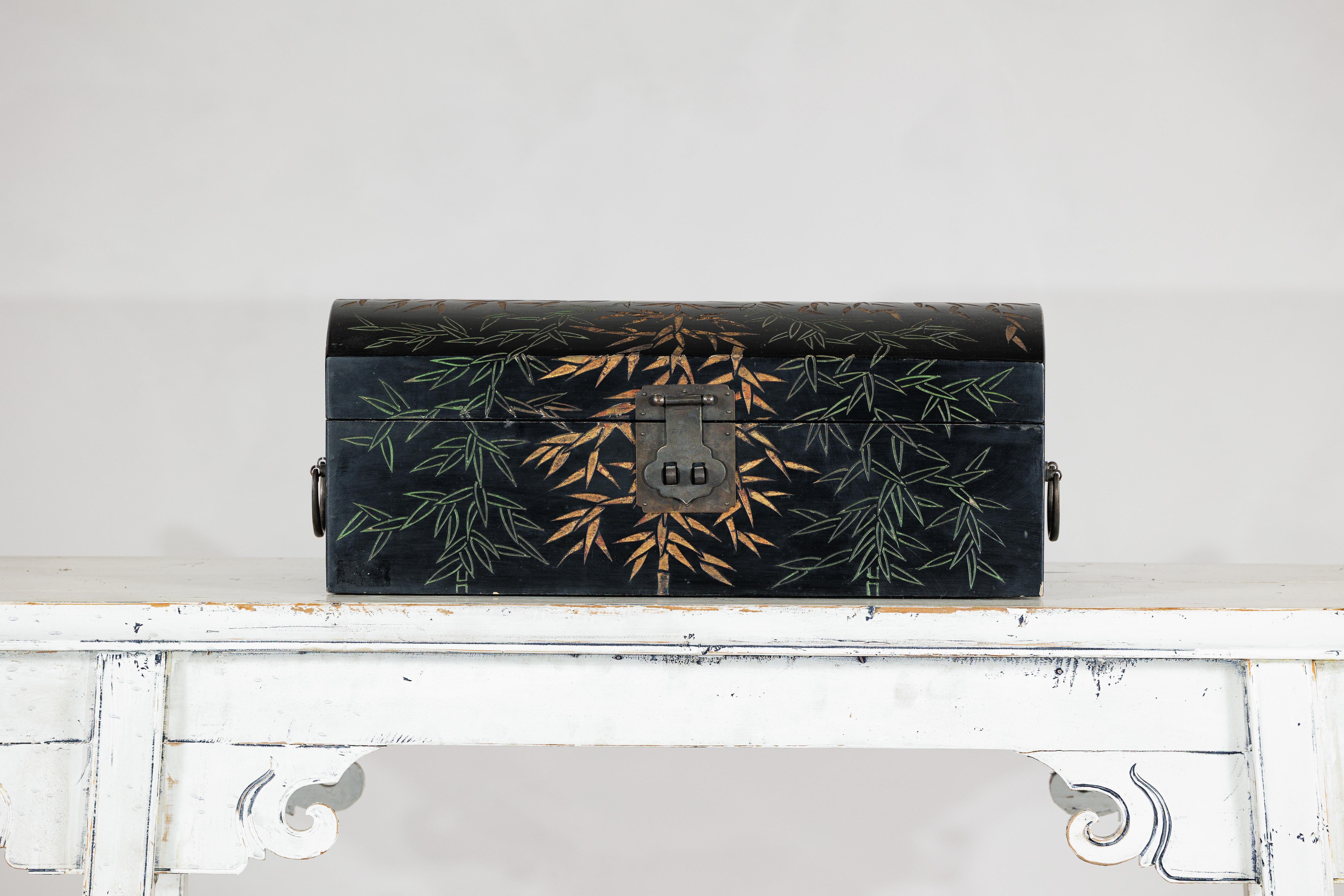 Scatola decorativa cinese d'epoca, realizzata in legno e rifinita in lacca nera lucida, con la superficie delicatamente ornata da un motivo di bambù e foglie verdi dorate. Il disegno, eseguito con pennellate sottili e fluide, cattura l'eleganza e il
