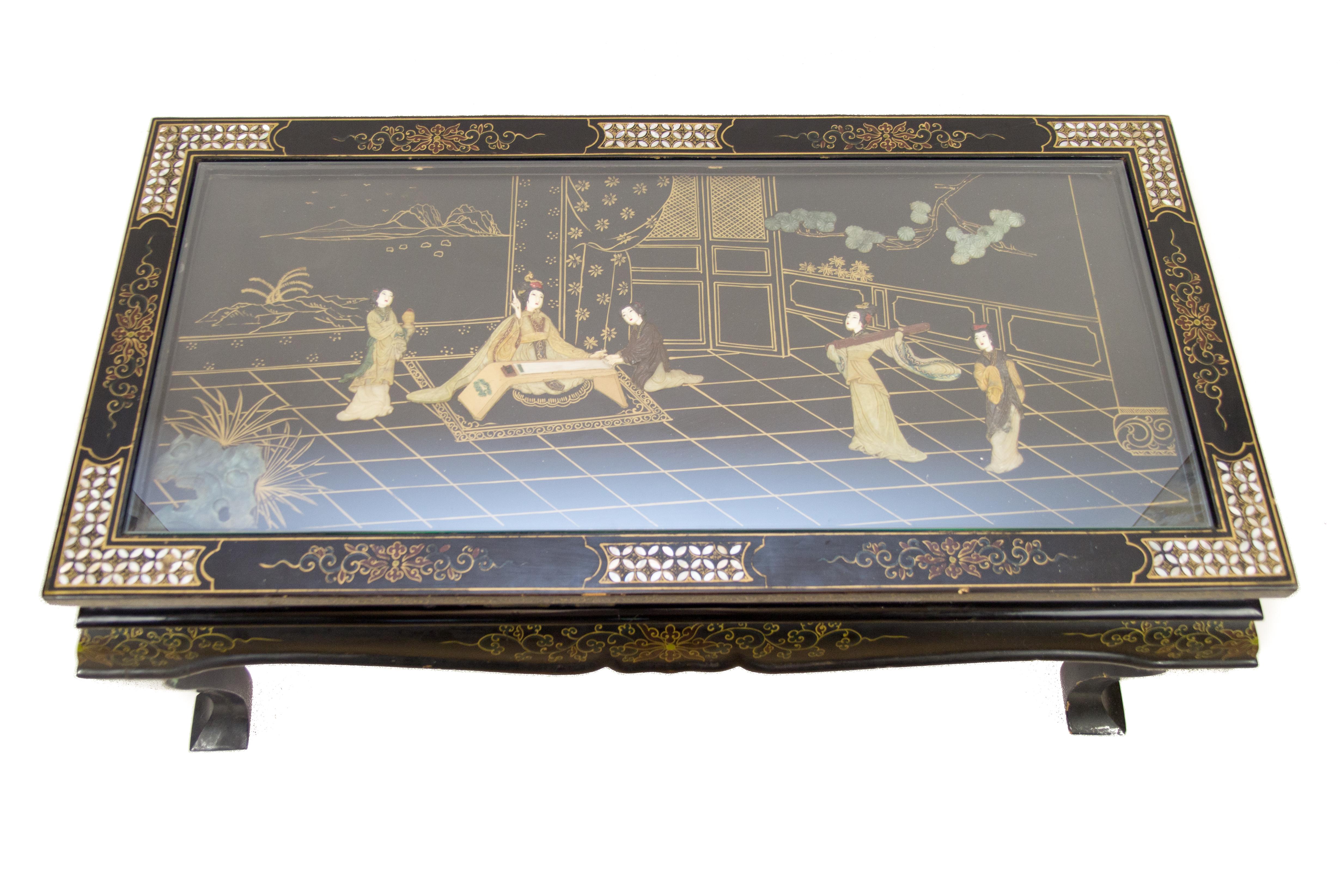 A beautiful vintage Chinese coffee table in lacquered and painted wood from the 1950s. The wooden, rectangular frame is decorated with painted floral details and mother of pearl inlays. A rectangular glass in the top protects the delicately sculpted