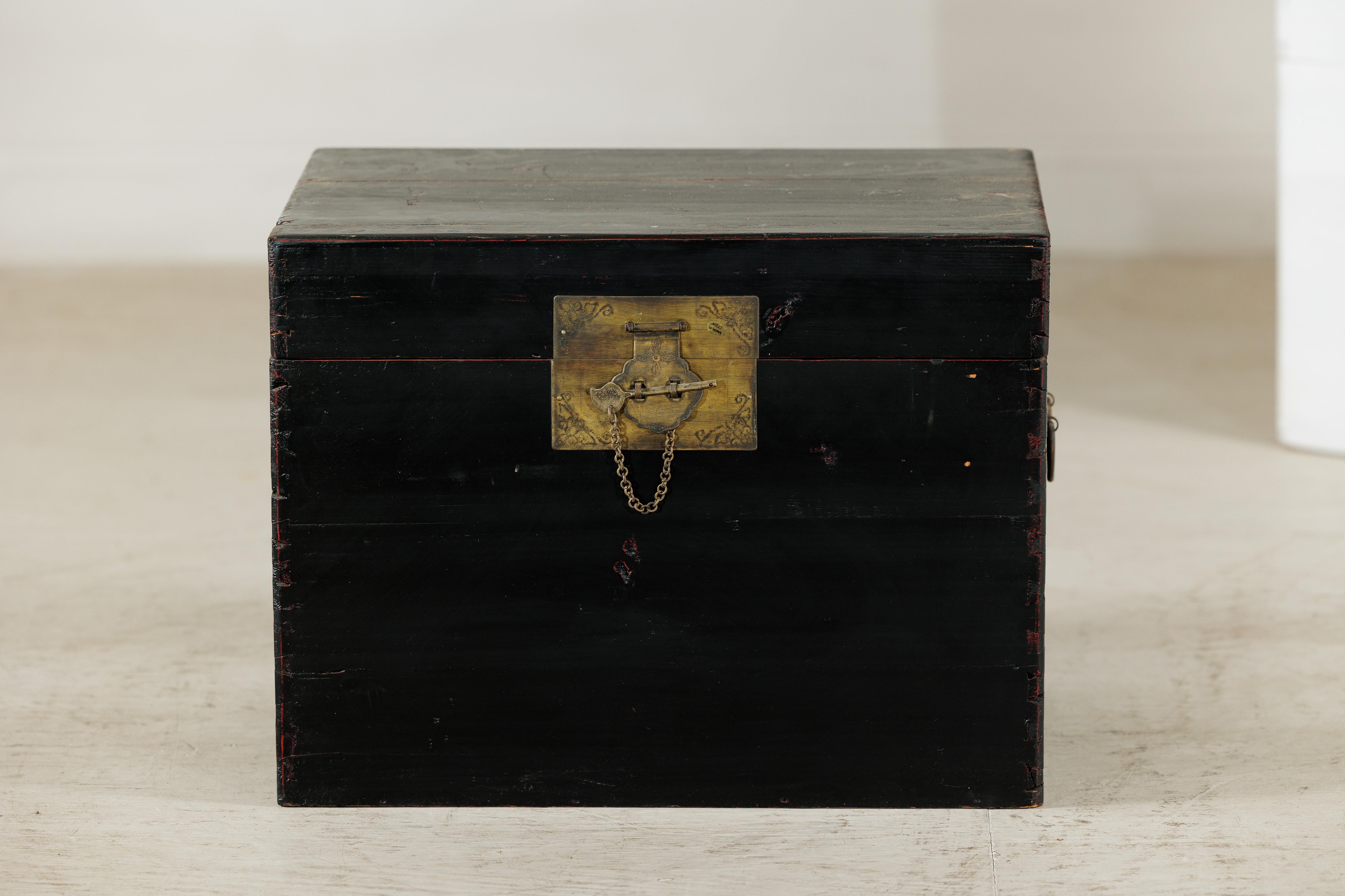 Questo baule cinese vintage, laccato nero e impreziosito da ottone brillante, offre spazio e stile. Questo baule presenta una raffinata forma rettangolare rifinita con una superficie laccata nera, impreziosita da accessori in ottone caldo. La parte