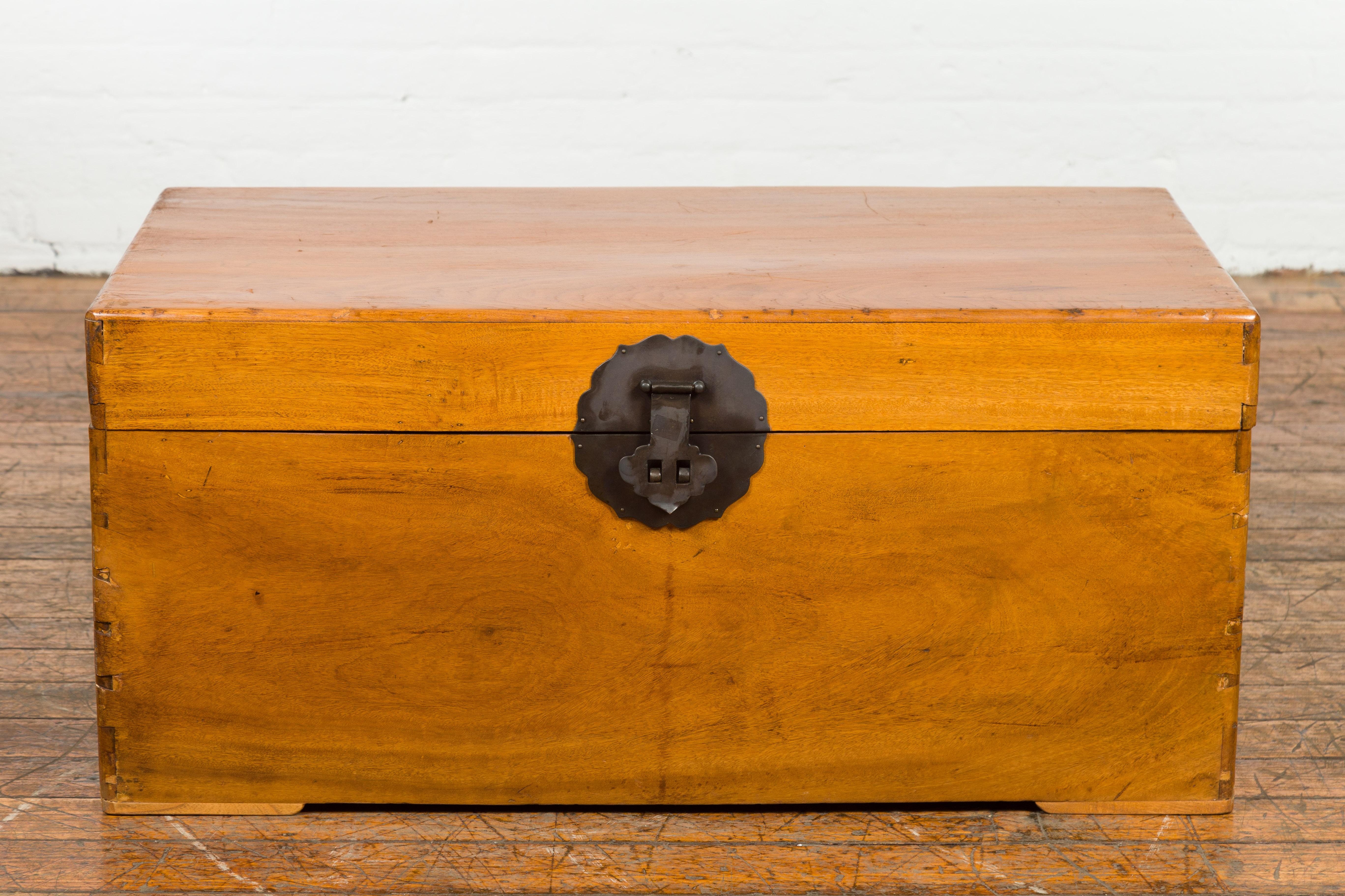 A vintage Chinese wooden blanket chest from the mid 20th century with iron hardware, lateral handles and dovetail construction. Hailing from the mid-20th century, this vintage Chinese wooden blanket chest is a merger of artful design and practical