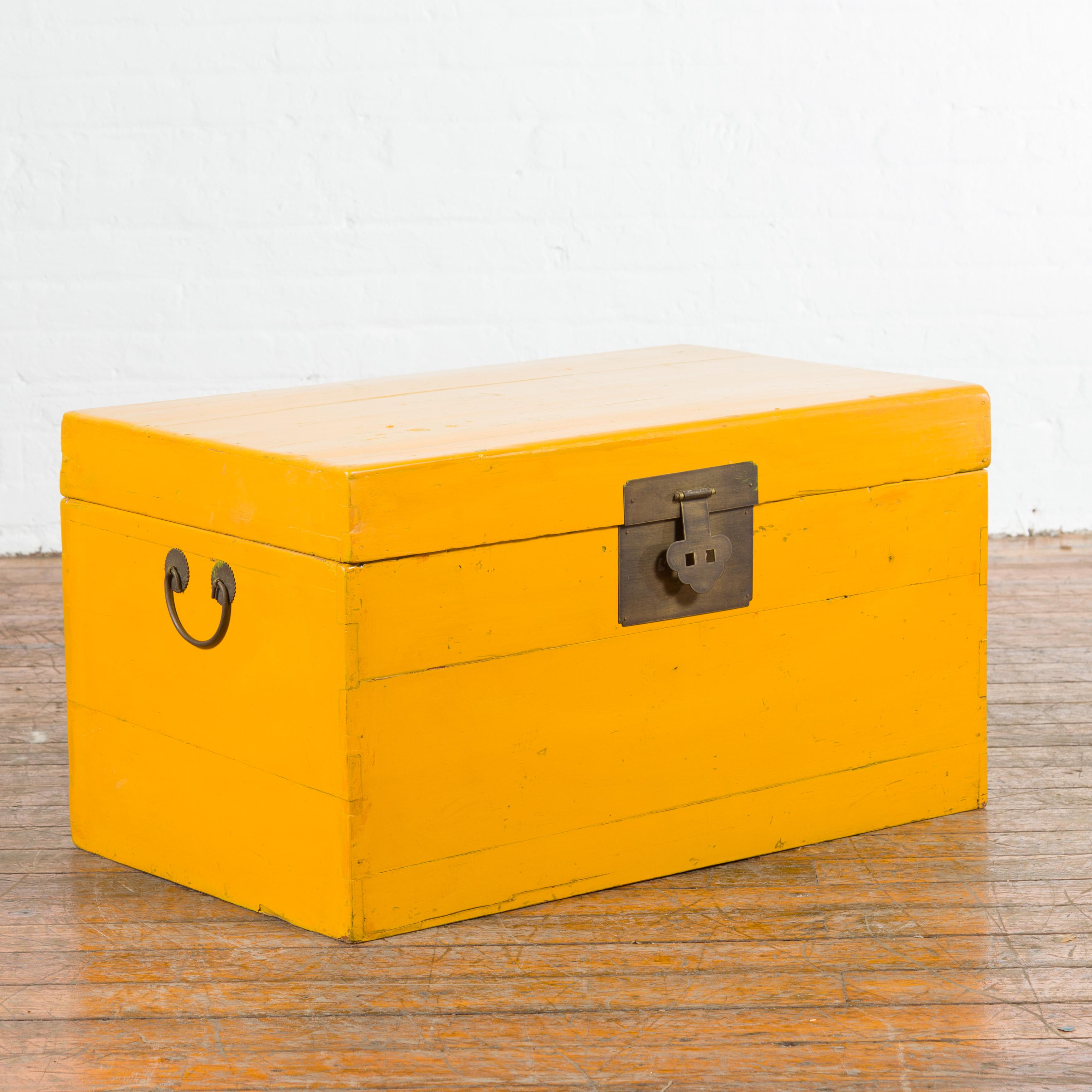 A Chinese vintage blanket chest from the mid-20th century, with yellow patina. Created in China during the midcentury period, this blanket chest draws our attention with its vivid yellow lacquer perfectly complimented by the traditional brass