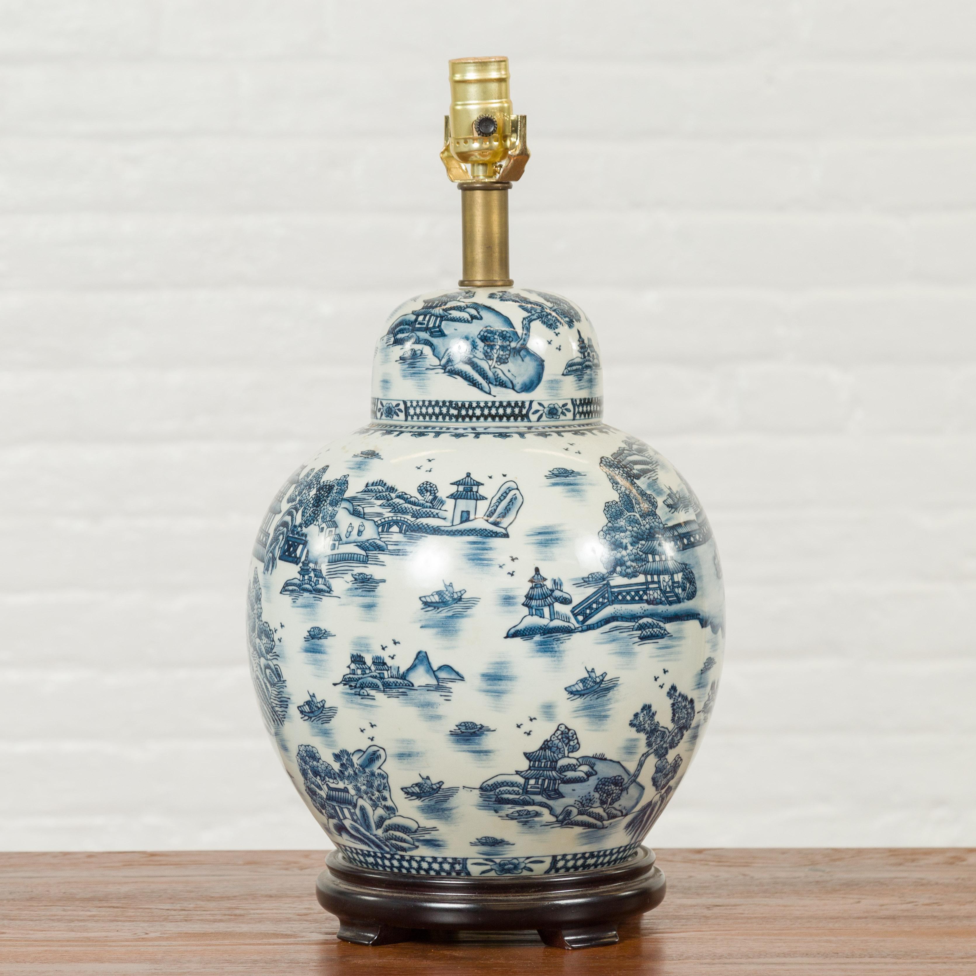 A Chinese vintage blue and white porcelain table lamp from the mid-20th century with landscape and architecture patterns. Born in China during the midcentury period, this blue and white porcelain vase has been made into a table lamp. Raised on a