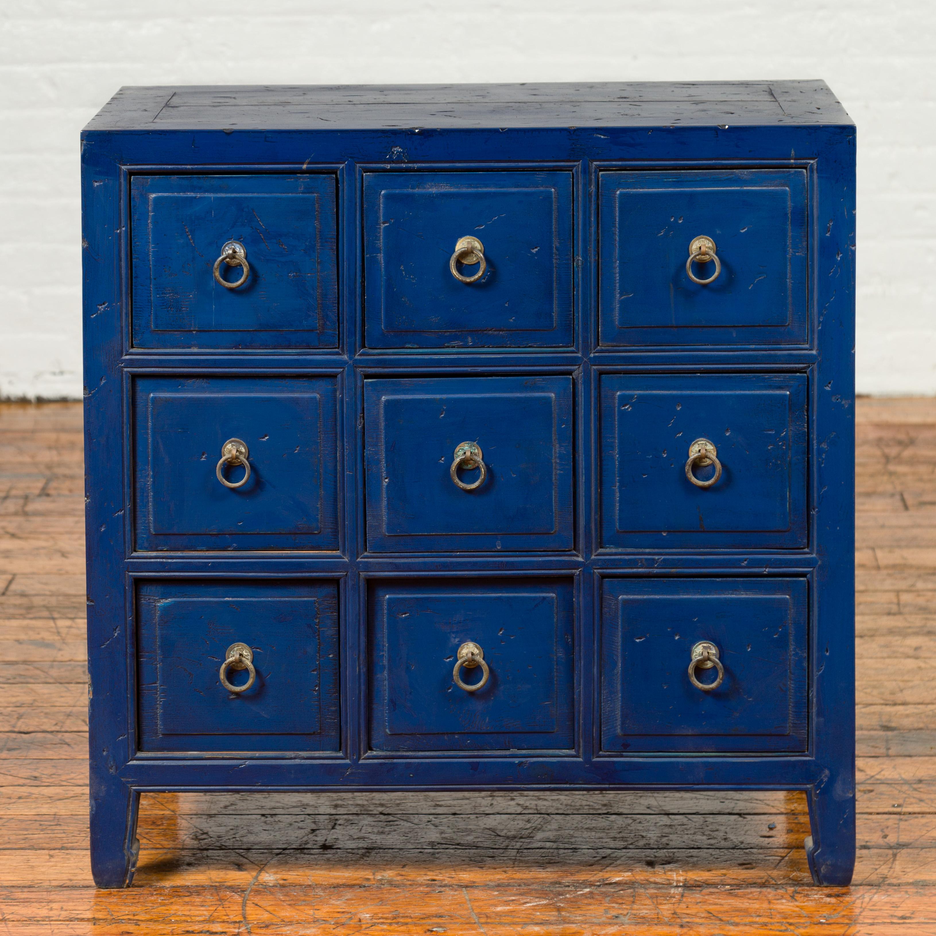 A Chinese vintage blue painted nine-drawer apothecary bedside chest from the mid-20th century, with brass pulls. Born in China during the midcentury period, this apothecary chest features a rectangular top, sitting above a perfectly organized