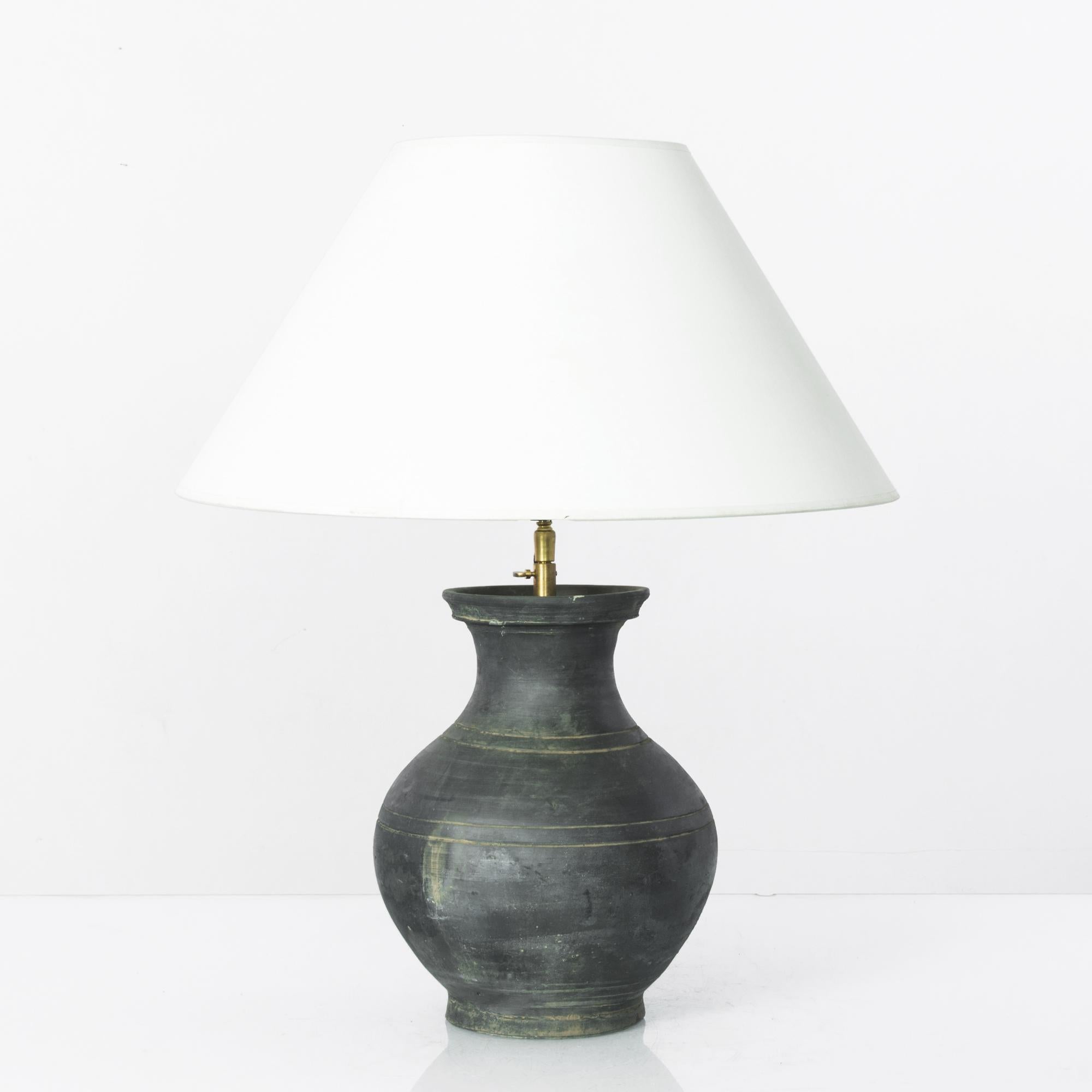 This finely crafted vintage Chinese vase has been fitted with an adjustable brass fixture and E26 lighting socket. Polished brass meets the textural carved and black glazed surface for an uncompromising contrast. Textured glazes, attractive colors