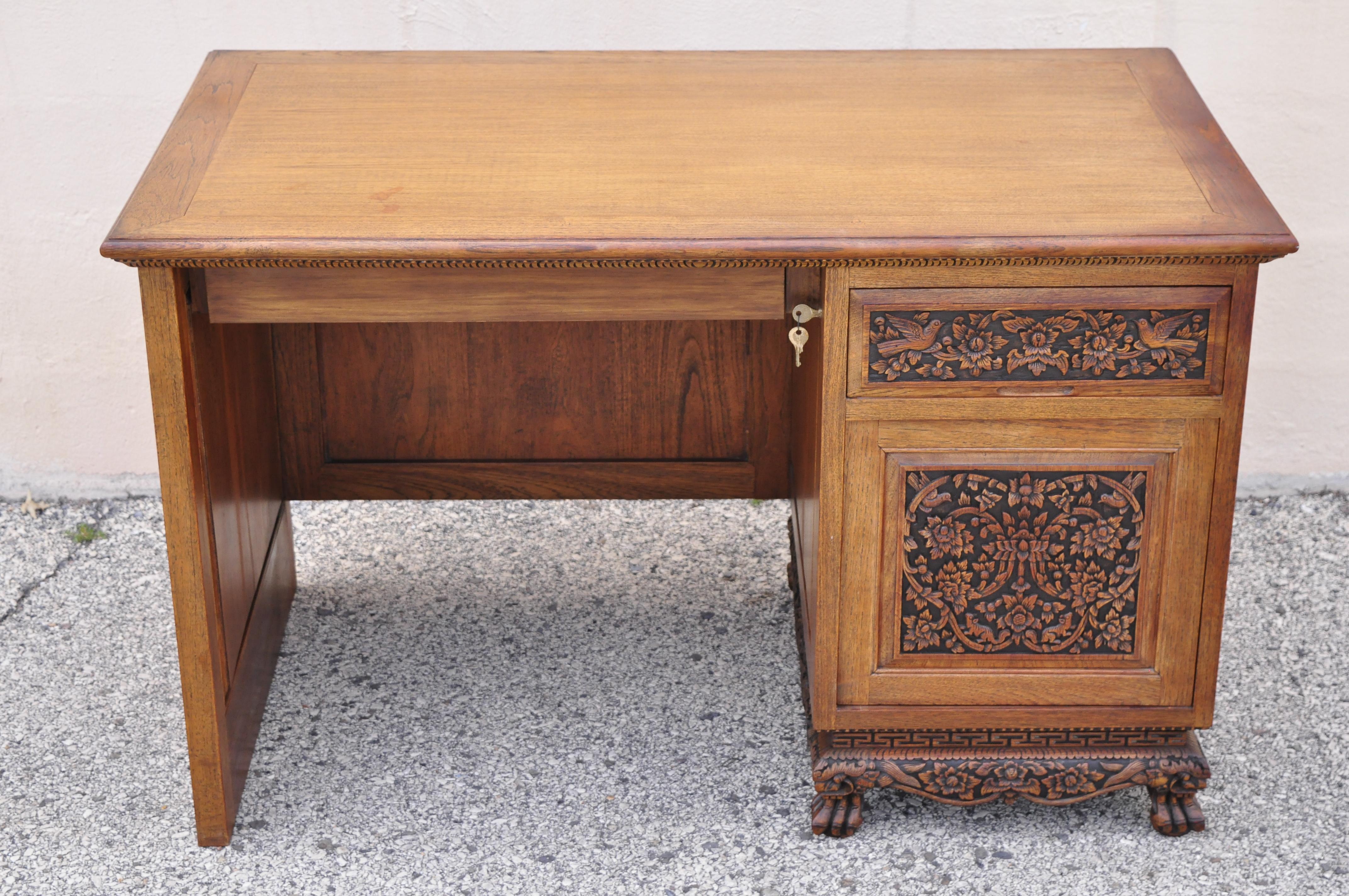 Vintage Chinese carved mahogany pedestal desk with flowers birds and leafy scrolls. Item features ornately carved throughout with flowers, birds, and leafy scrollwork carved faces to feet/base, solid wood construction, 1 swing door, working lock and